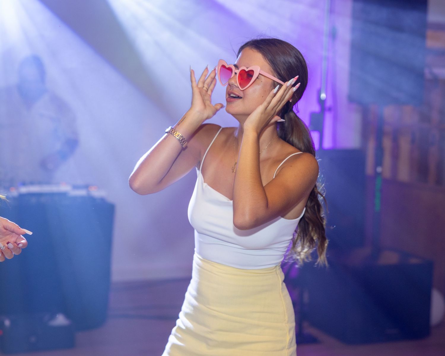 Eine Frau mit roter Sonnenbrille tanzt im farbigen Licht.