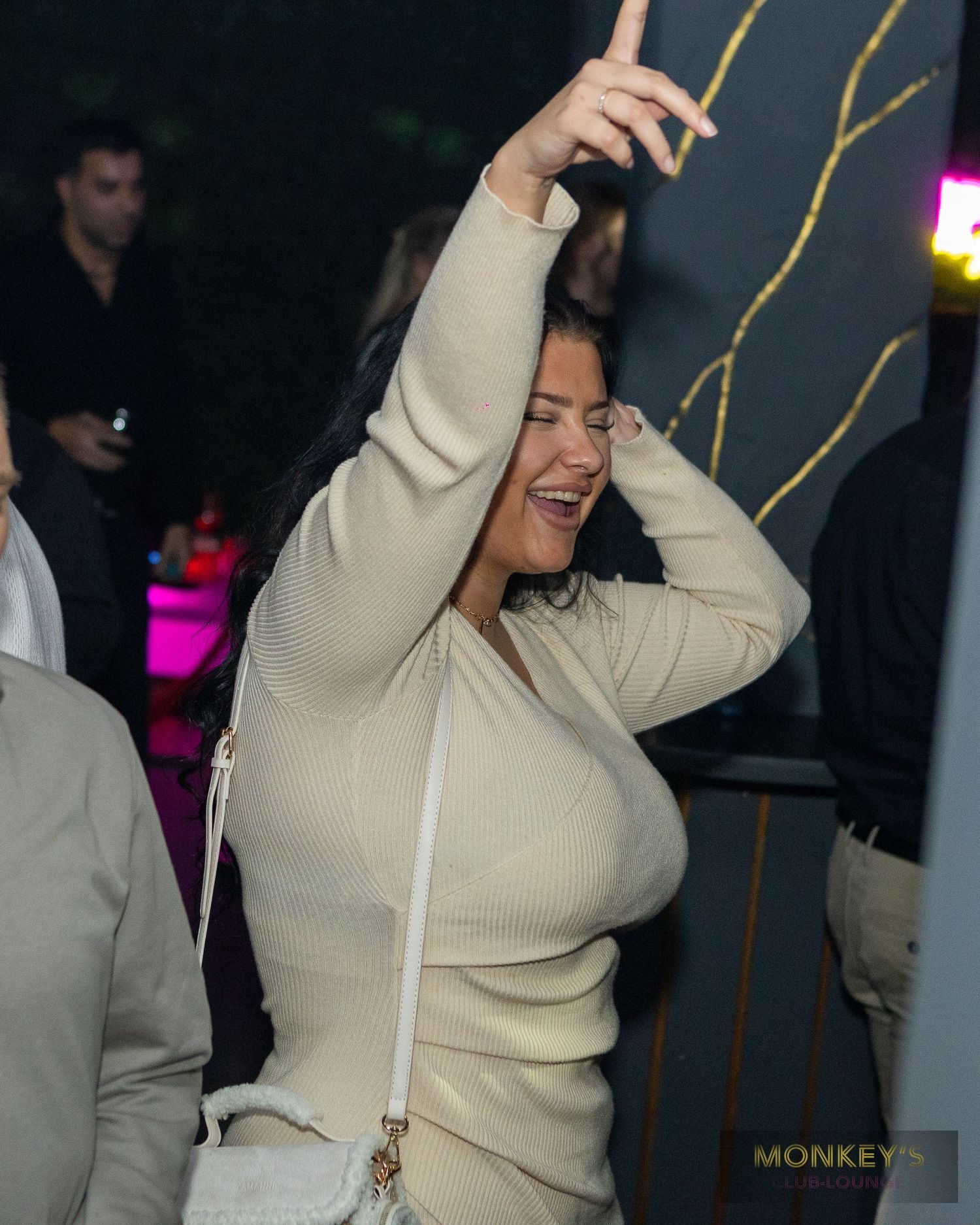 Eine Frau hebt auf der Tanzfläche im Monkey’s Club beide Arme.