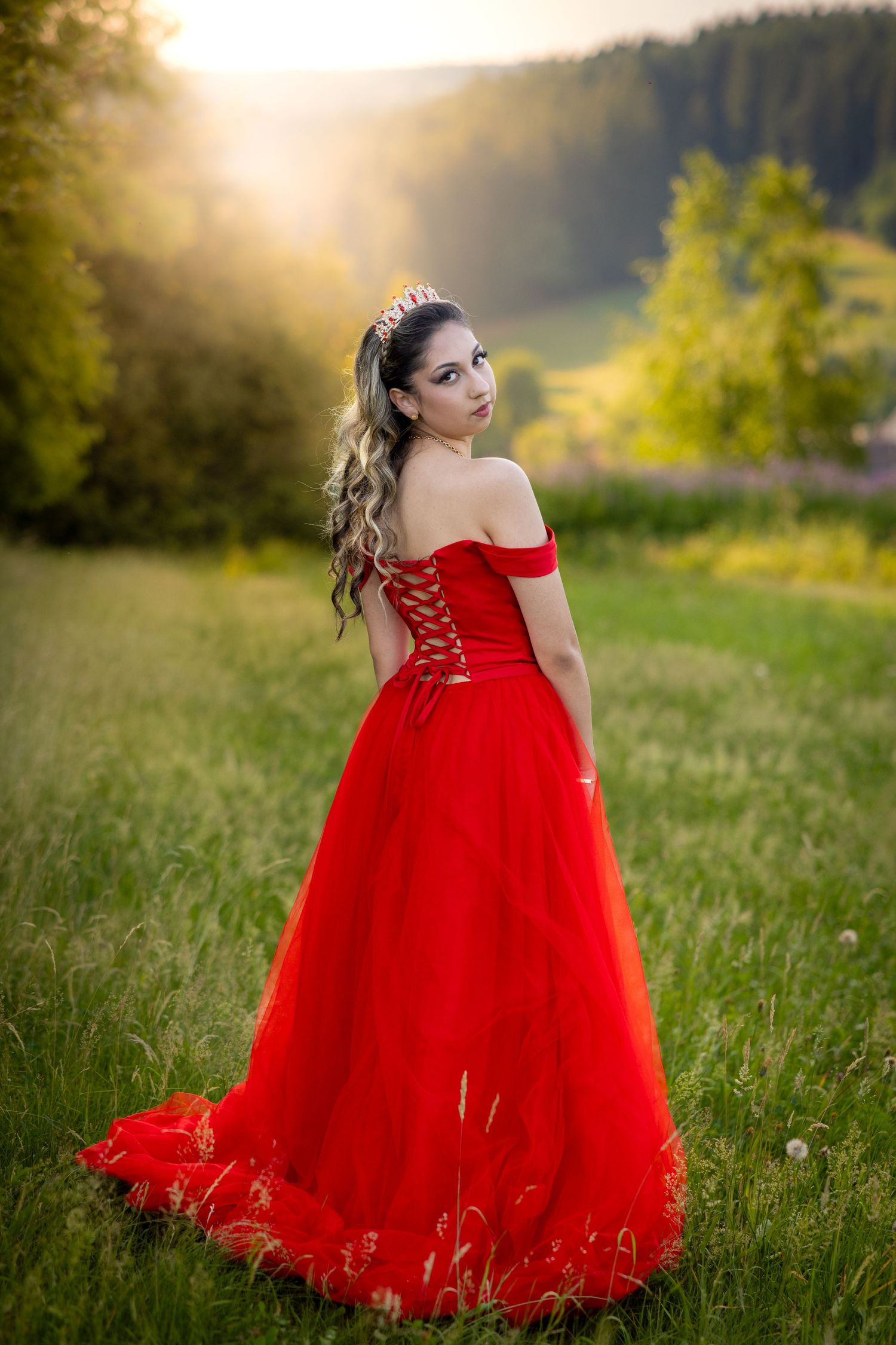 Lorena im roten Kleid vor dem schattigen Rand des Waldes