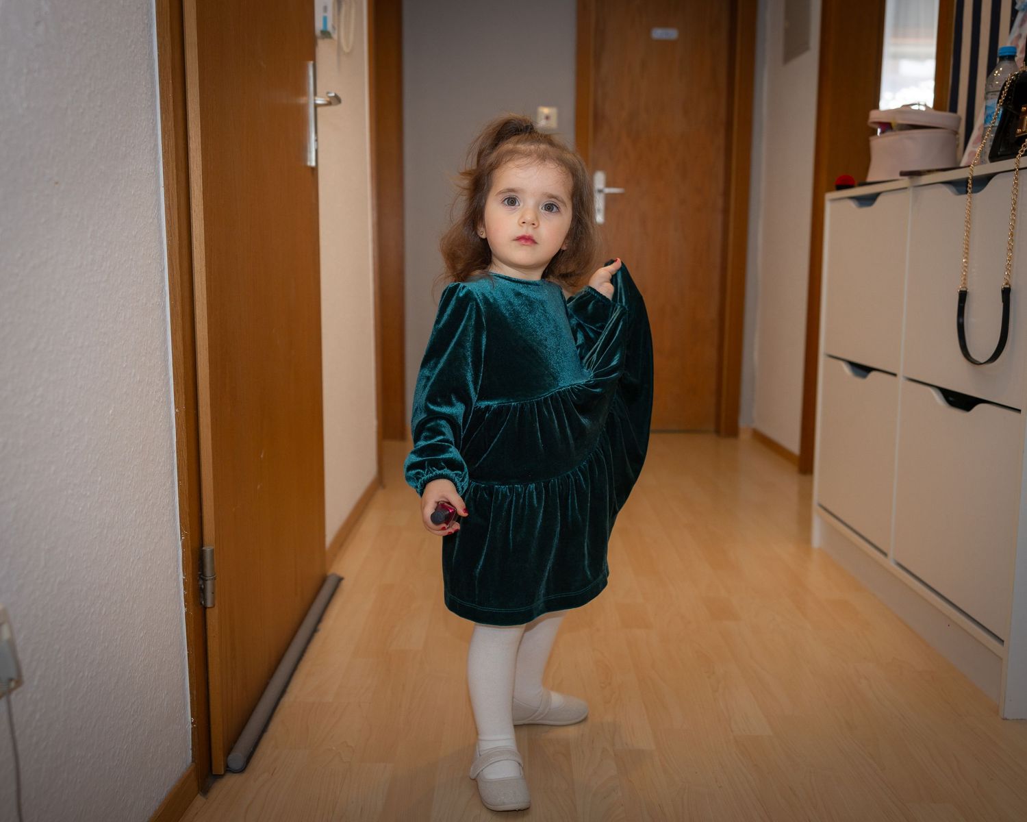 Ein Mädchen wartet im Flur, während sich die Familie auf die Taufe vorbereitet