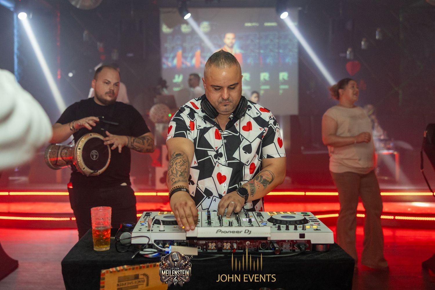 Zwei Männer stehen hinter dem DJ-Pult im roten Licht des Club Meilenstein.