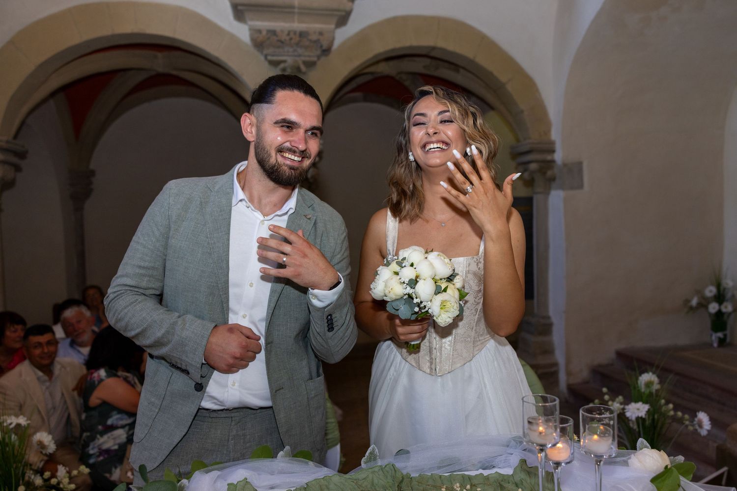 Naomi und Sergiu lachen nach der Trauung und zeigen ihre Eheringe.