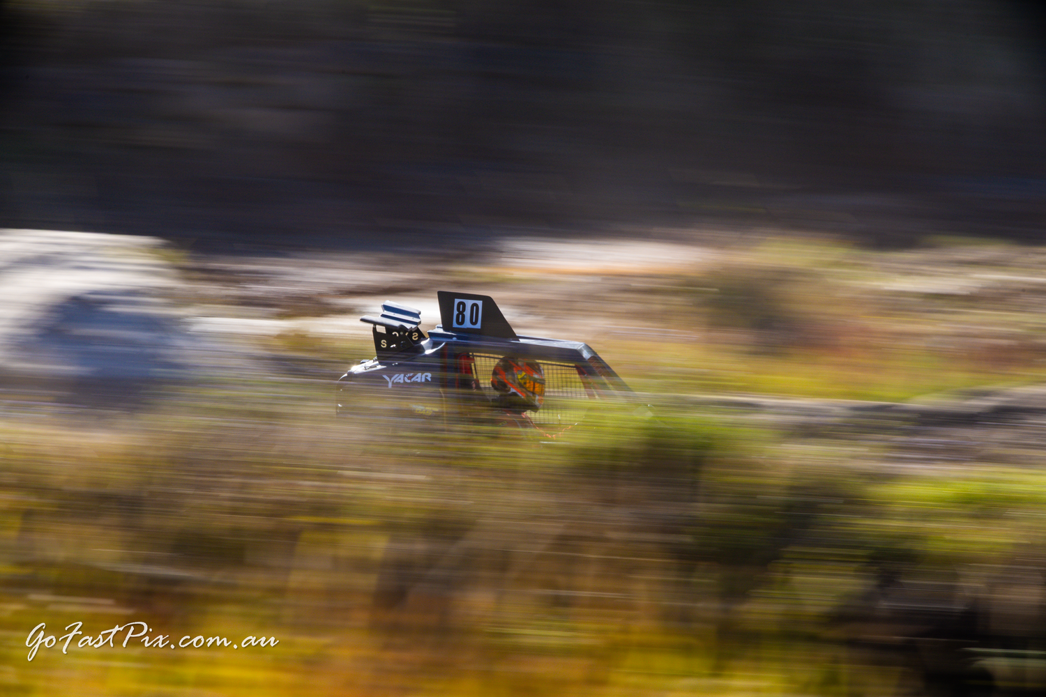 Motion blur panning shot of a black off-road race truck speeding across terrain.