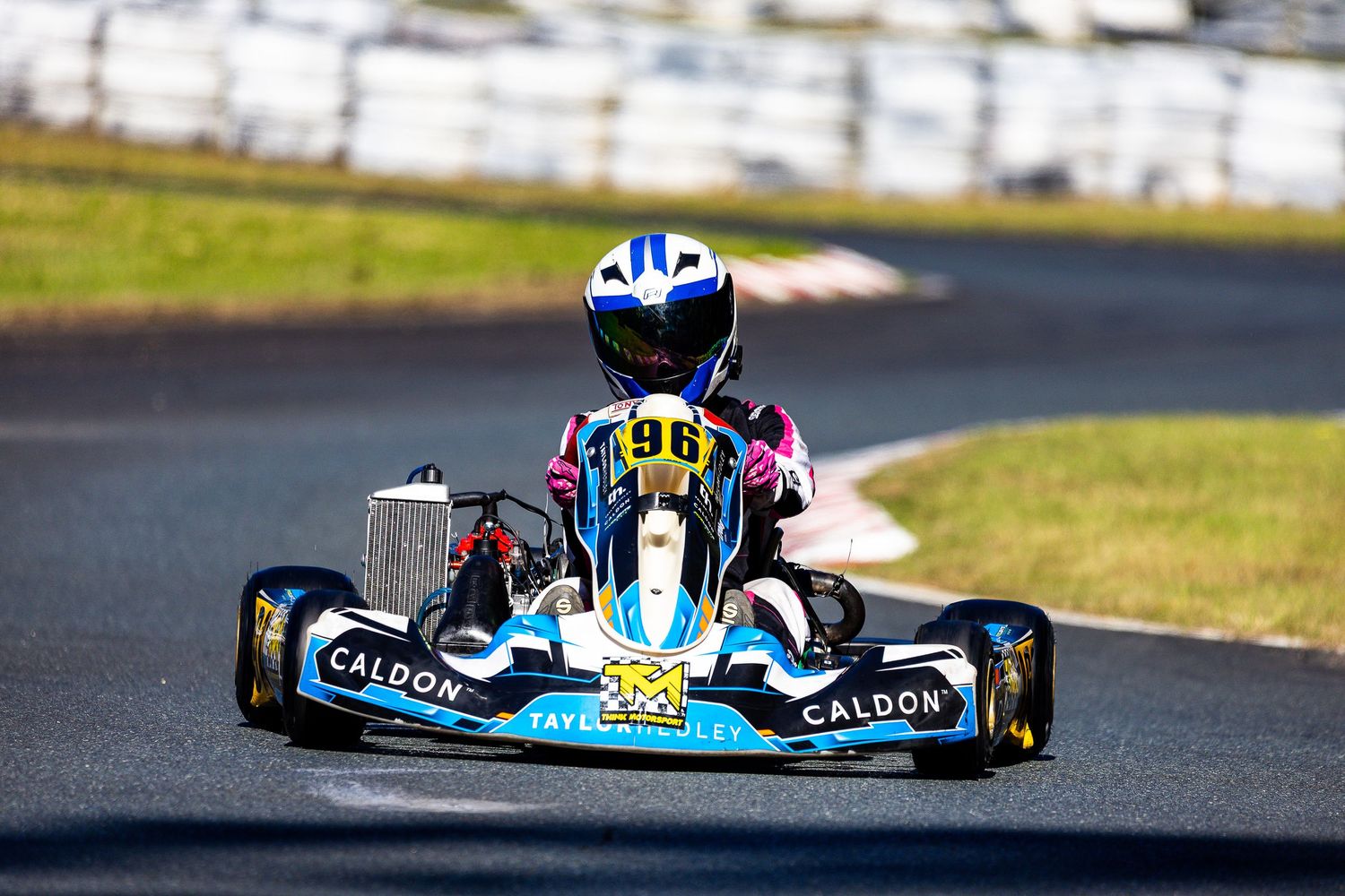 Young racer in kart #96 with Caldon sponsorship navigates a turn on a professional karting circuit.