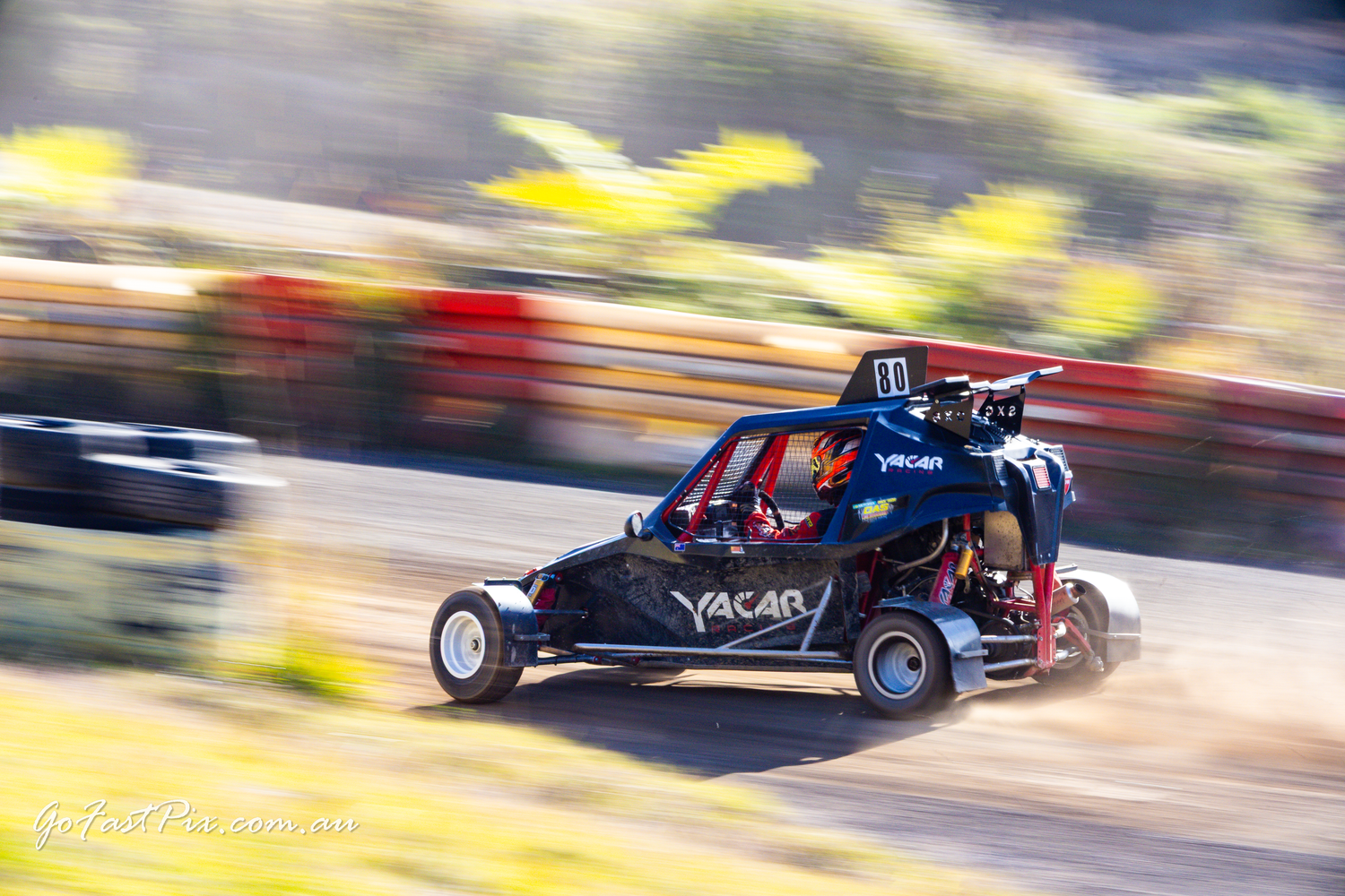 Yacar branded racing buggy captured with motion blur on a dirt circuit.