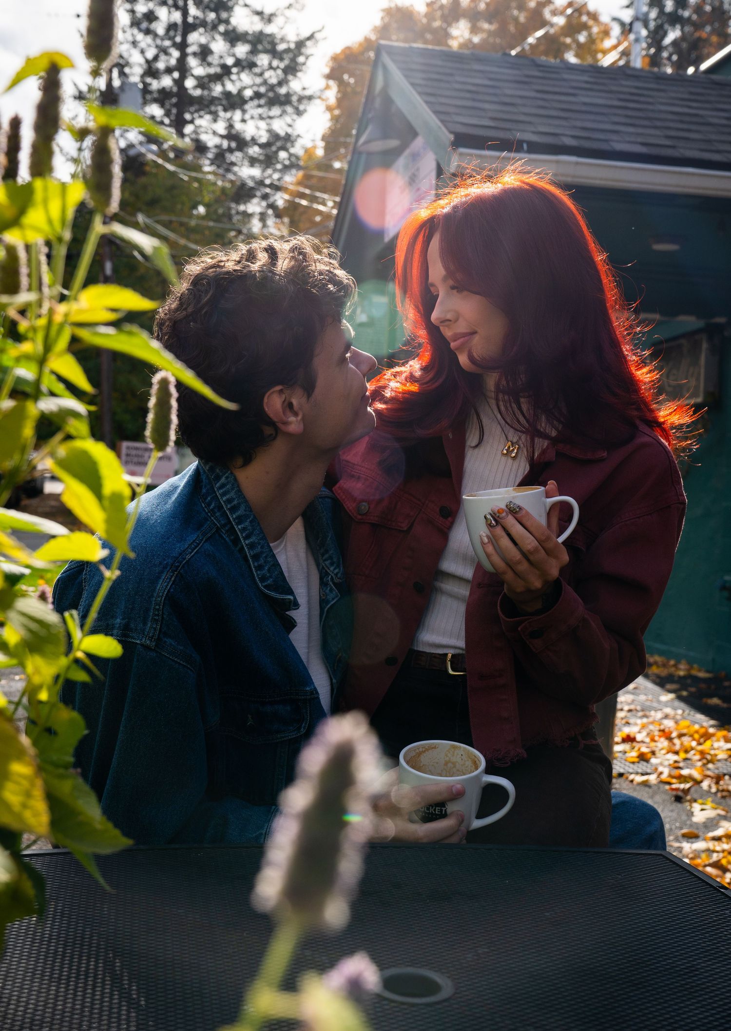 A couple leans close together outside, both holding coffee cups, caught in a warm and intimate moment during their couples photo session.
