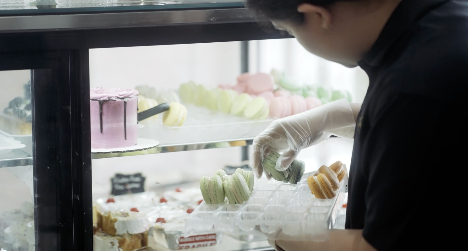 Person arranging desserts inside a bakery display case