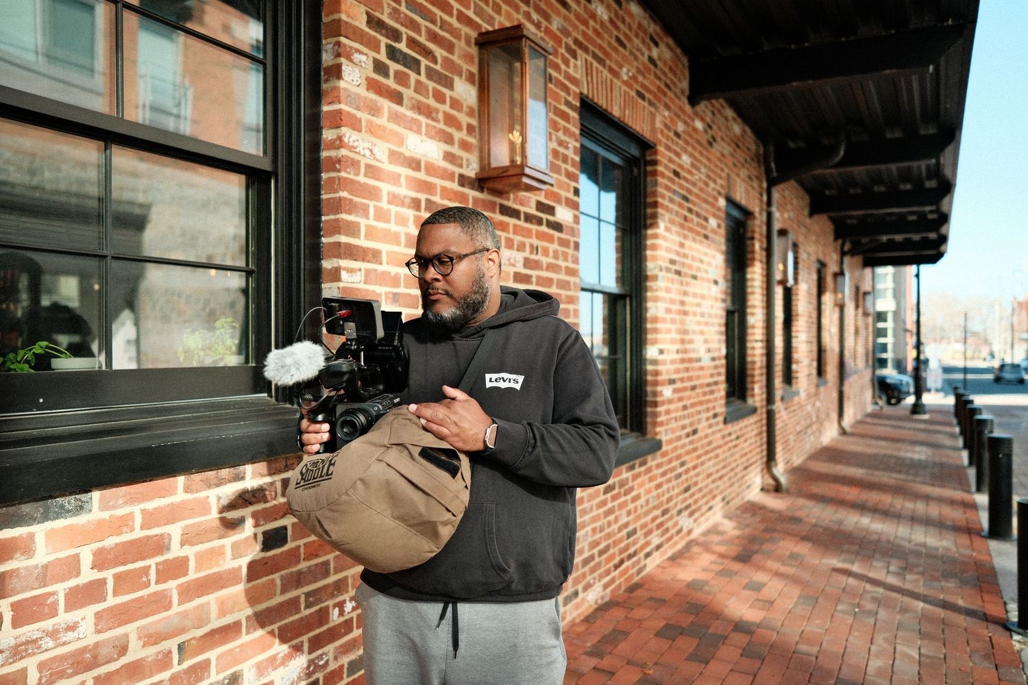 Jeffrey Hunter standing outdoors with camera gear near a brick building