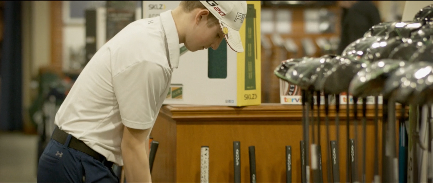 Golfer selecting clubs from a golf bag in a pro shop setting