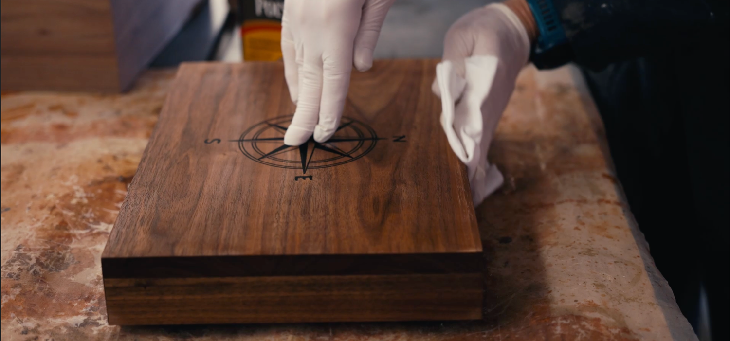 Hands applying a logo mark to a wooden product box