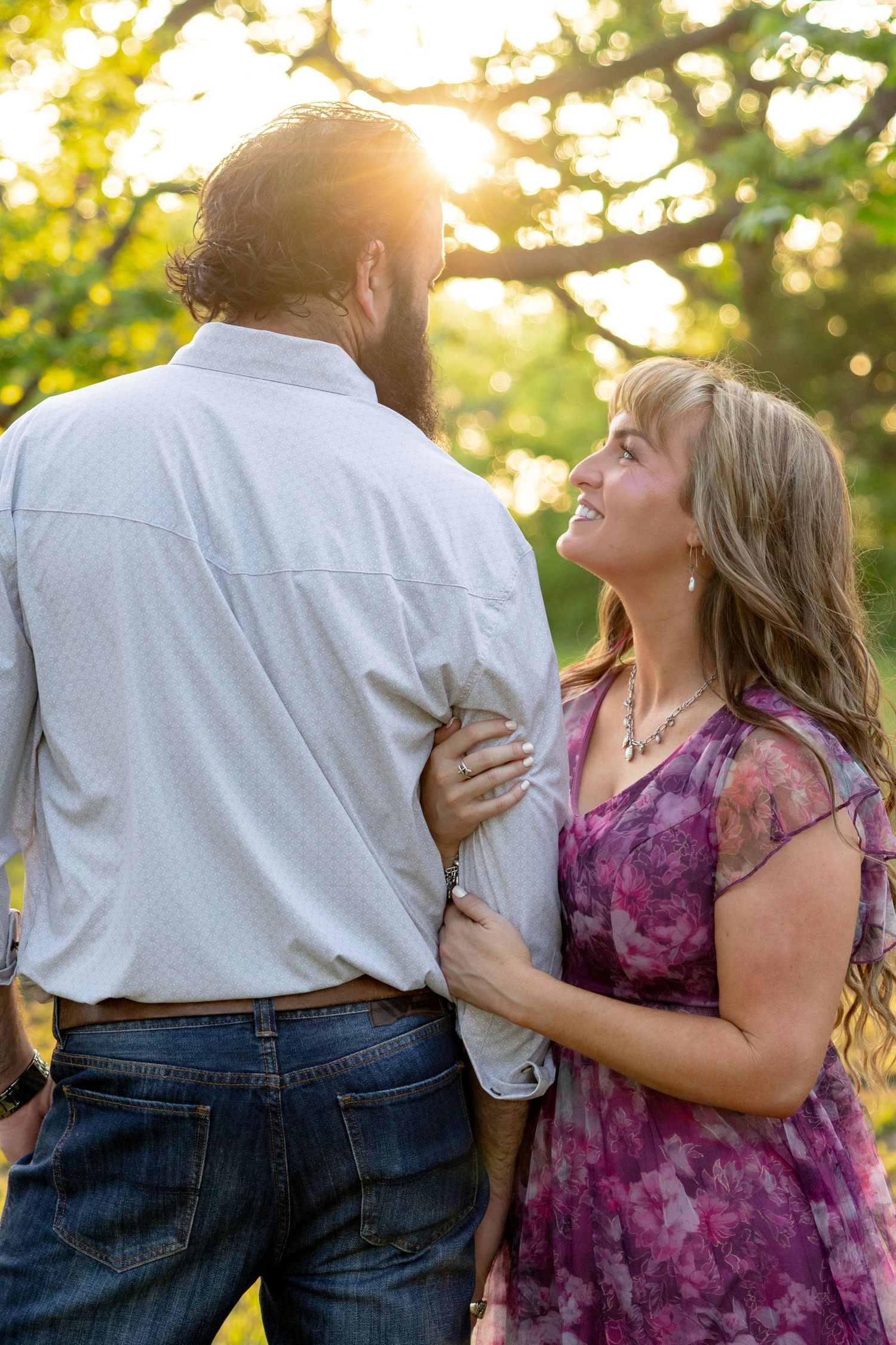 Woman in floral dress smiling up at her partner during a golden hour outdoor photo session. Stephenville Texas