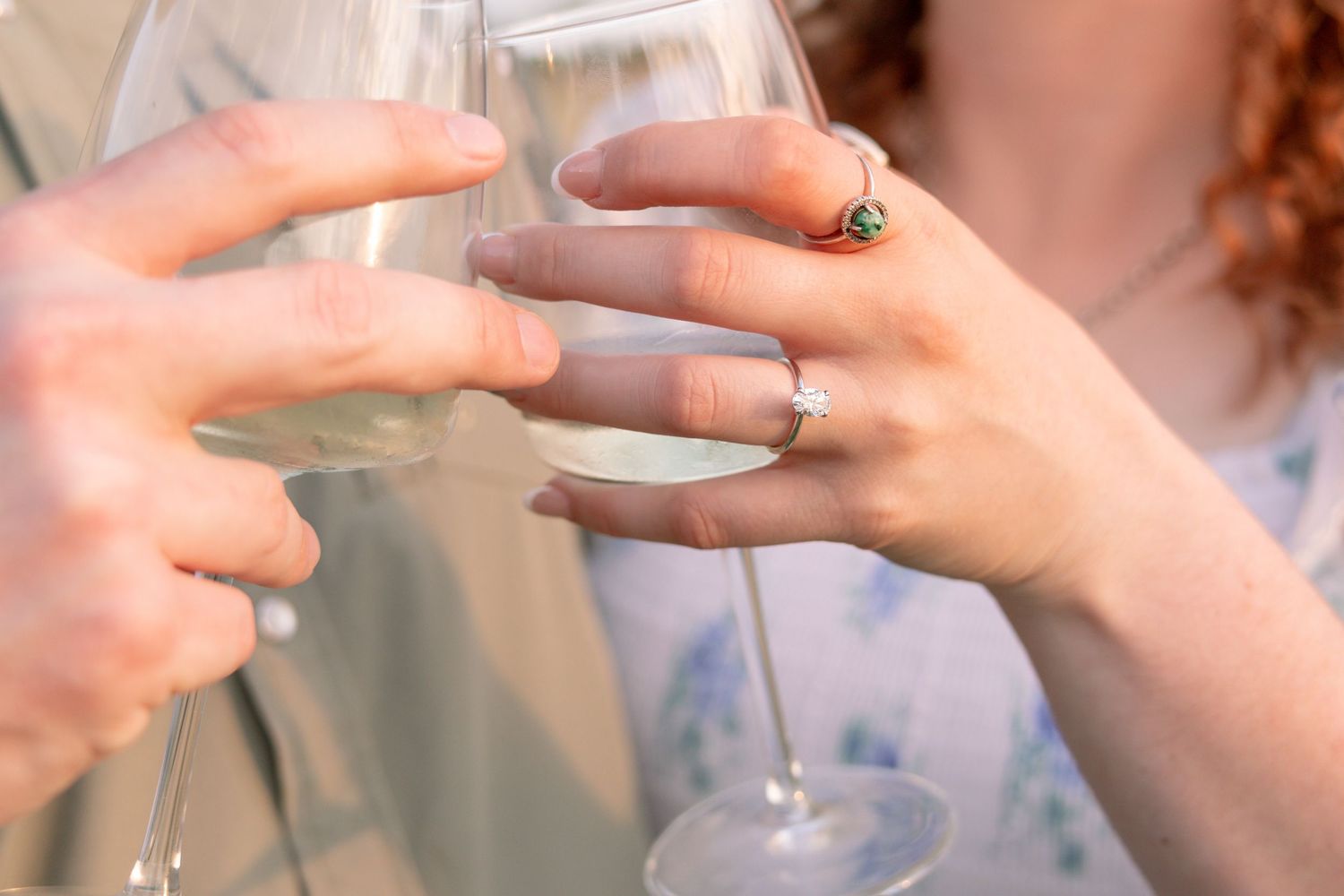 Close-up of couple clinking wine glasses showing diamond engagement ring on woman's hand. Stephenville Texas