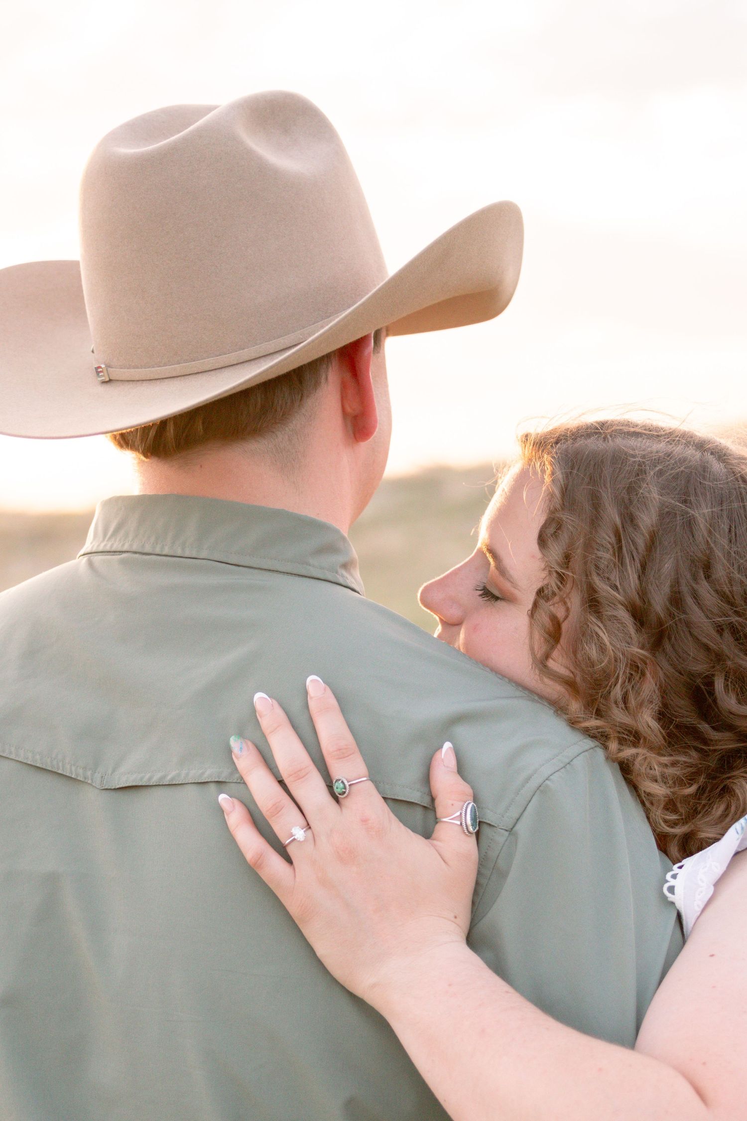 A woman rests her head on a mans shoulder as he wears a cowboy hat during a golden hour portrait.
Stephenville Texas