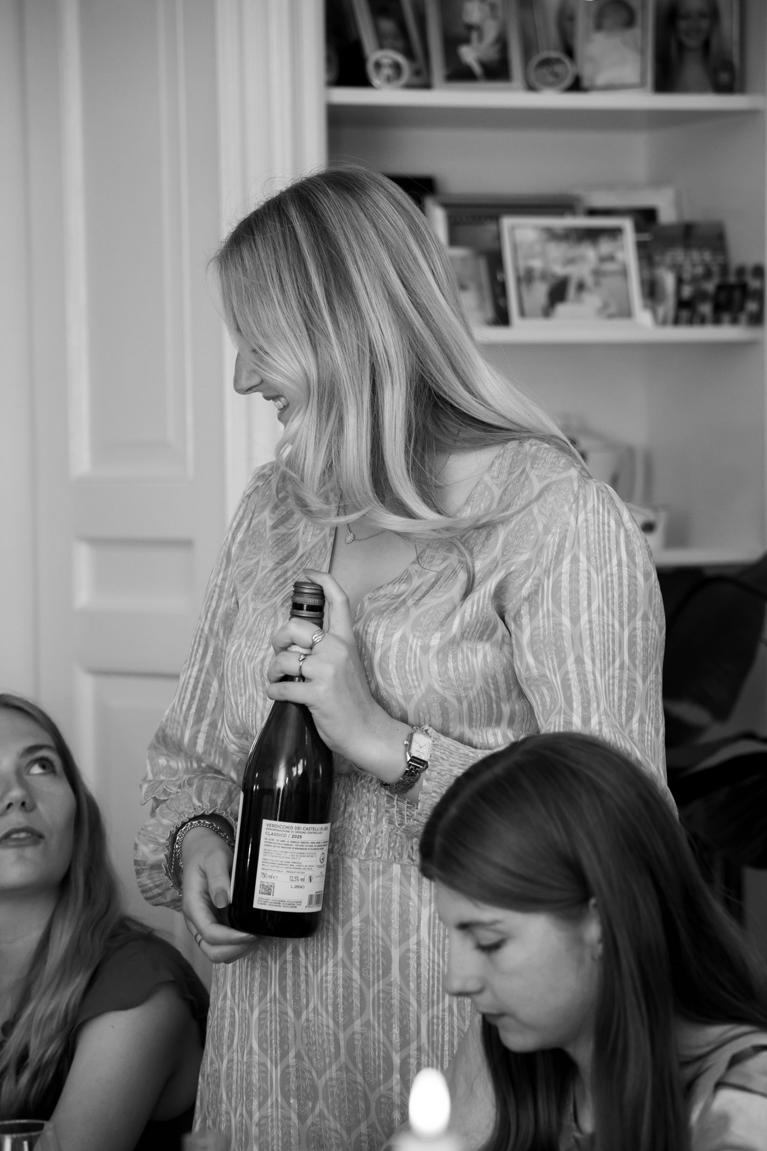 Blonde woman in elegant dress holding a wine bottle at a dinner party in black and white.
Evelijn - 21 Diner - Event shoot