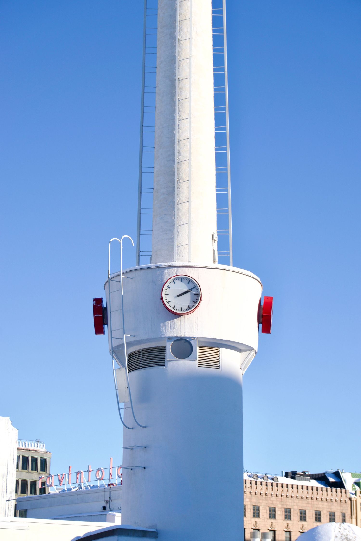 White ship funnel with clock and red lights against clear blue sky, with city buildings visible below.
Reizen - Lynn - Helsinki