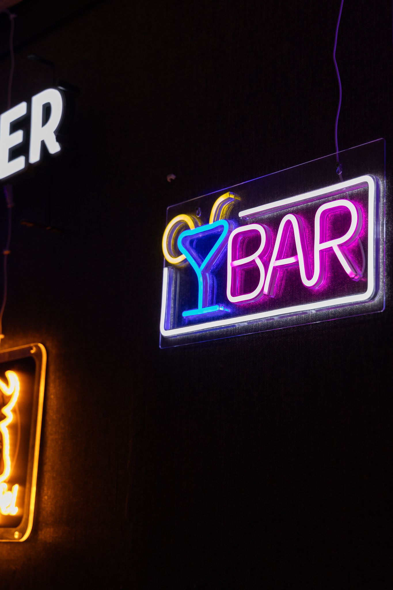 Glowing neon BAR sign with blue martini glass on dark wall, purple and white lights illuminating the night.
Yip's Hengelo - Bowlen - Brandin