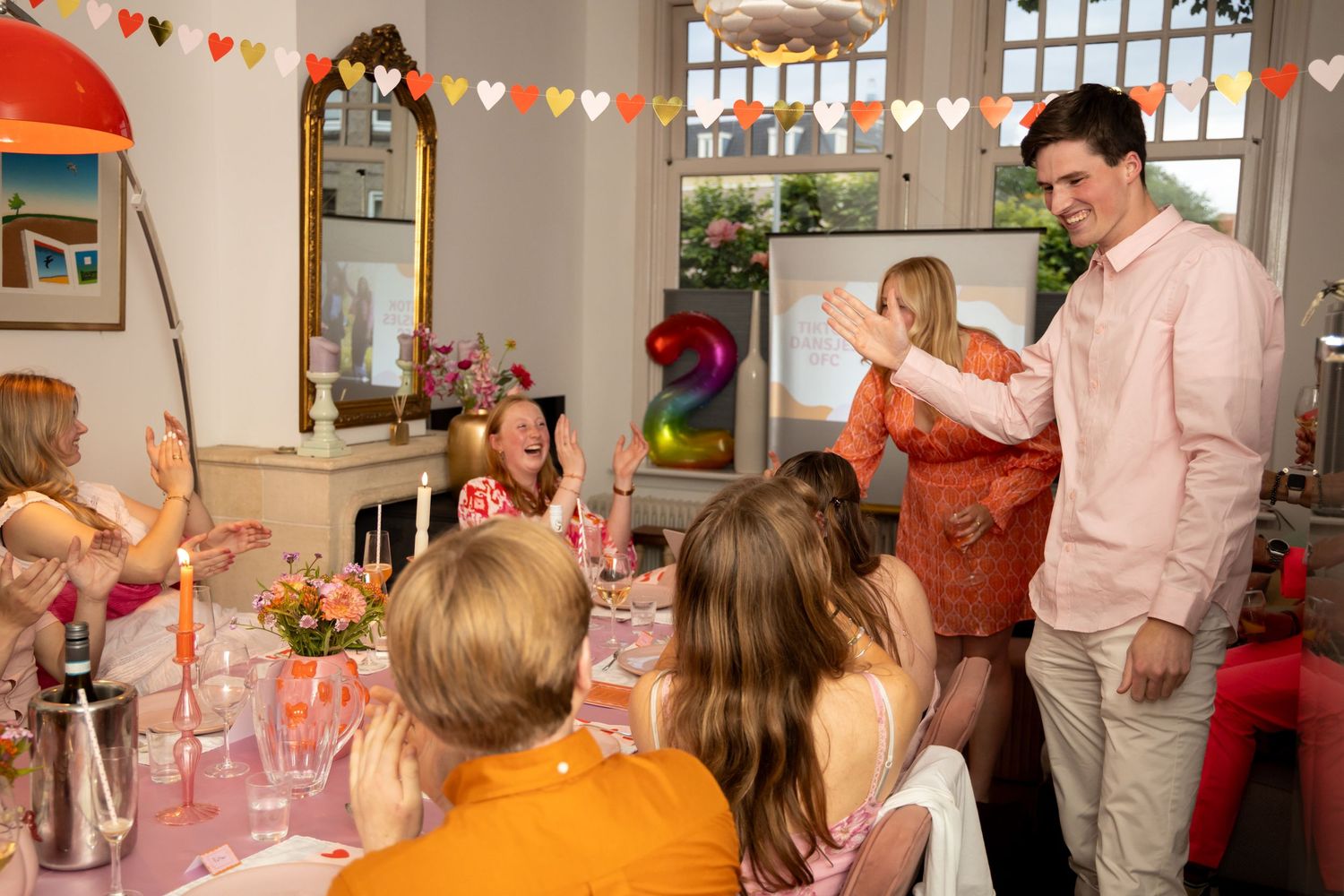 Group of people celebrating at colorful party with heart bunting decorations.
Evelijn - 21 Diner - Event shoot