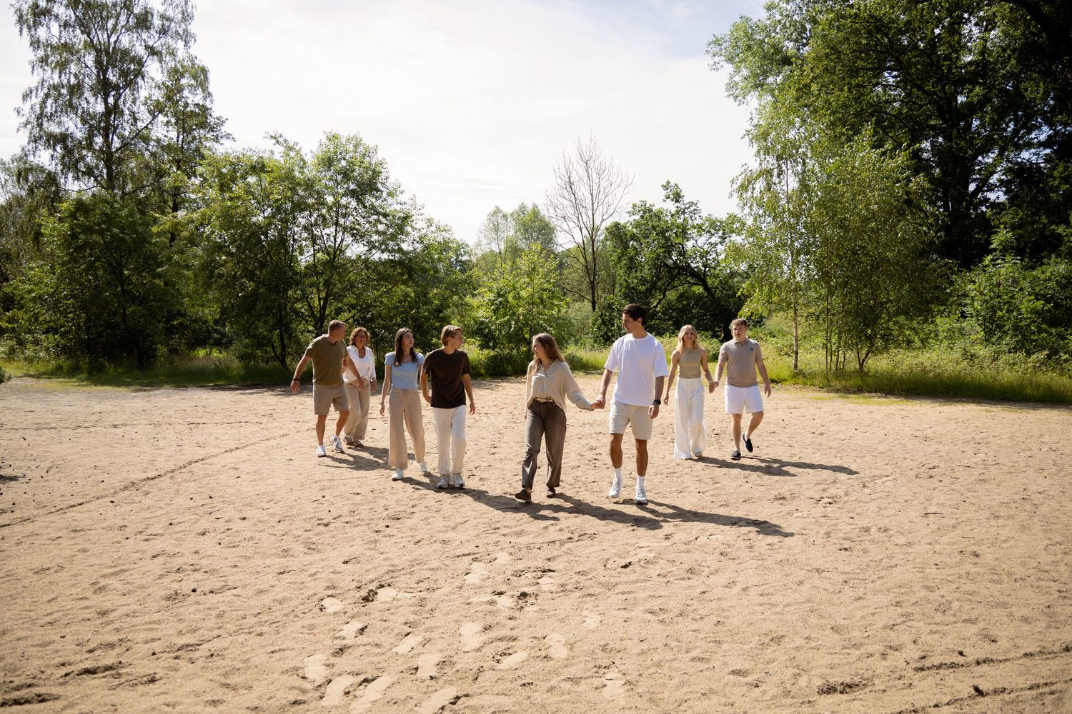 Family walking hand in hand across a sandy beach surrounded by lush green trees on a sunny day.
Familie Wormgoor - Familieshoot