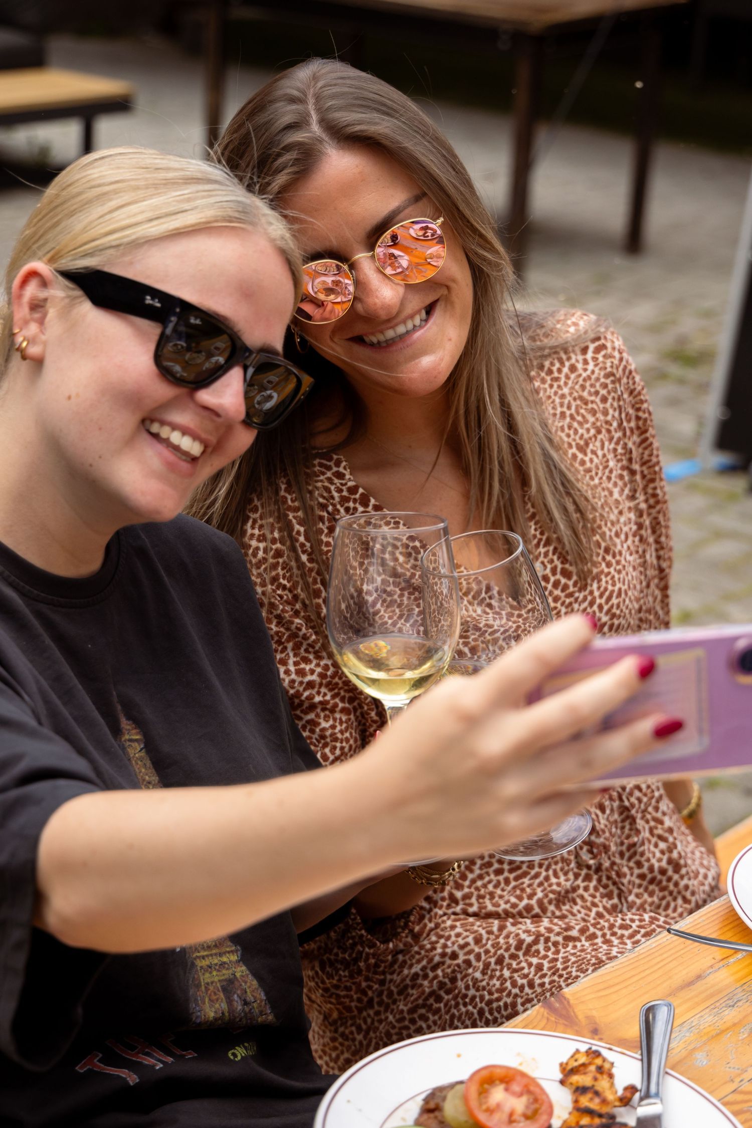 Two women taking a selfie at outdoor restaurant, with sunglasses, holding white wine.
Yips - BBQ - Brandingshoot