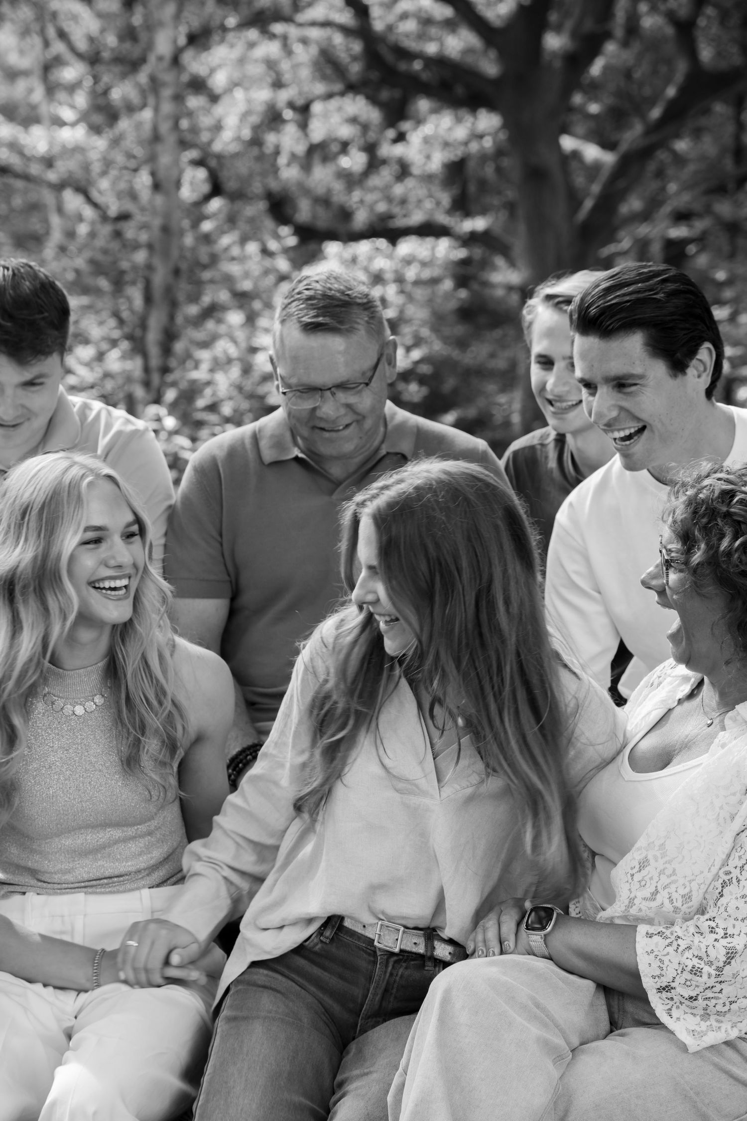 Black and white family portrait of multigenerational group laughing together outdoors under trees.
Familie Wormgoor - Familieshoot