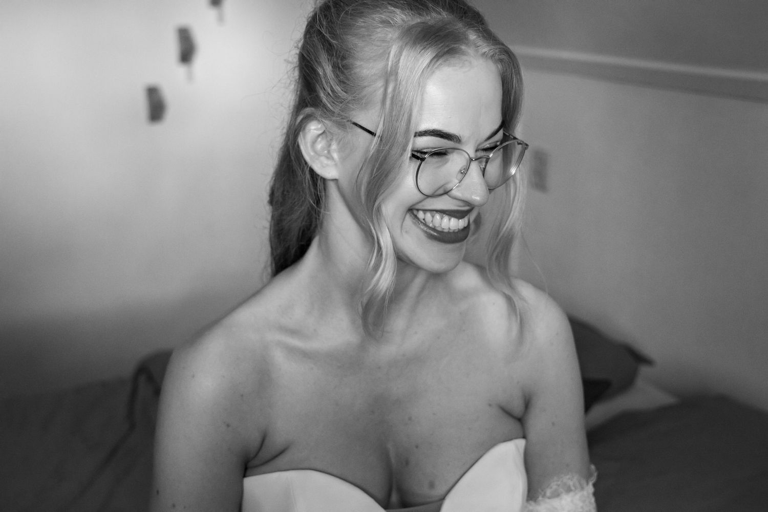 Smiling blonde woman wearing glasses in a black and white portrait photo.