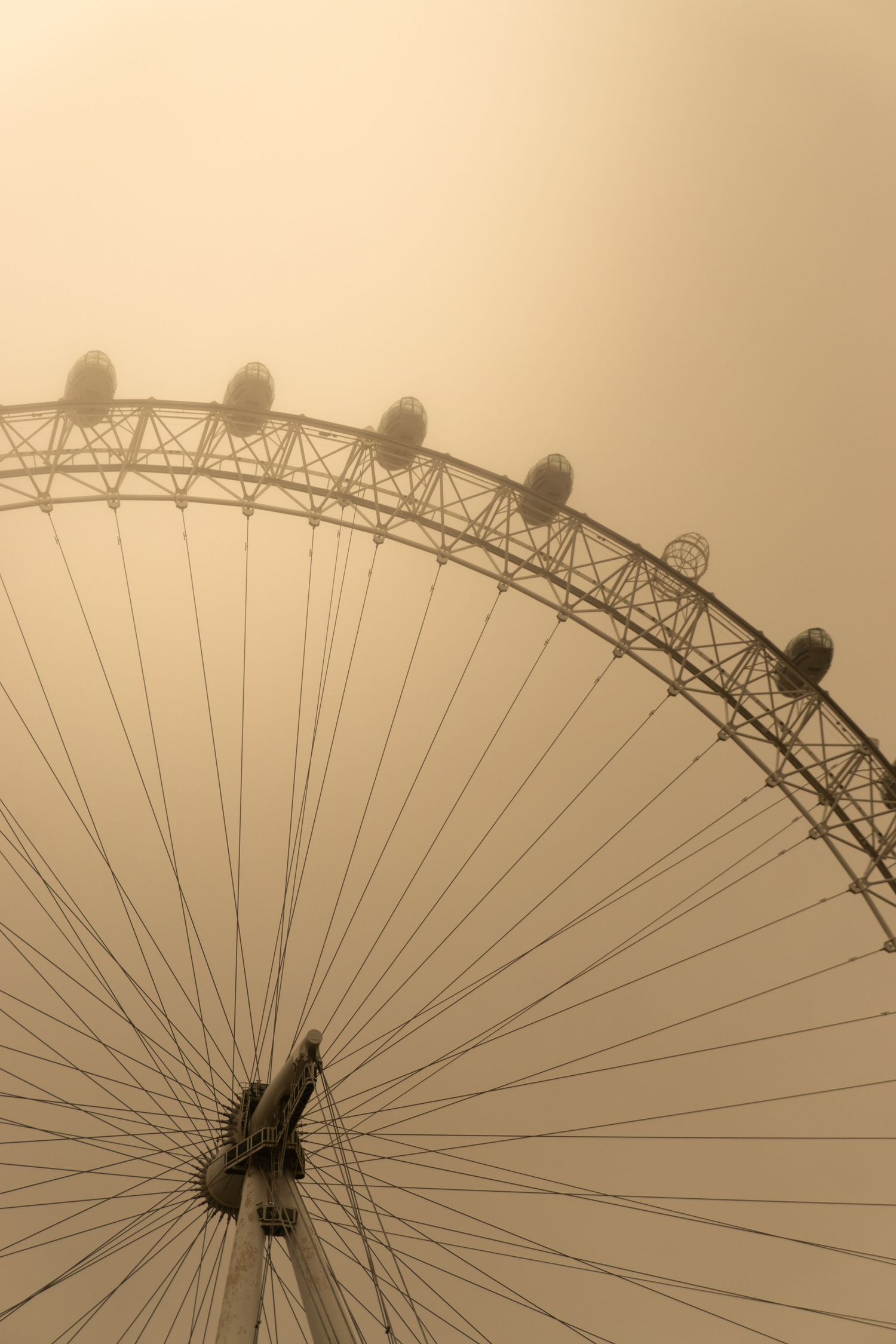 Sepia-toned London Eye Ferris wheel emerging through dense fog, showcasing its iconic capsules and spokes against a hazy sky.
Reizen - Lynn