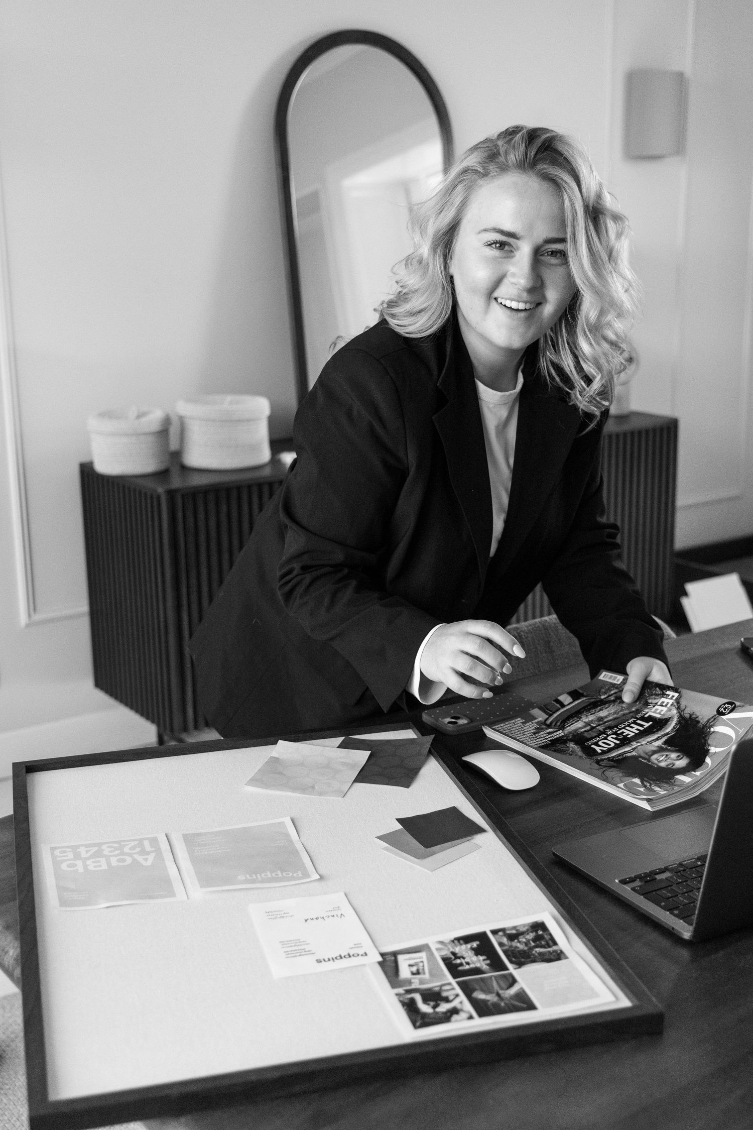 Smiling blonde woman in black blazer sits at desk with design mood board and laptop in stylish office.
Emma - Reefolution - Brandingshoot