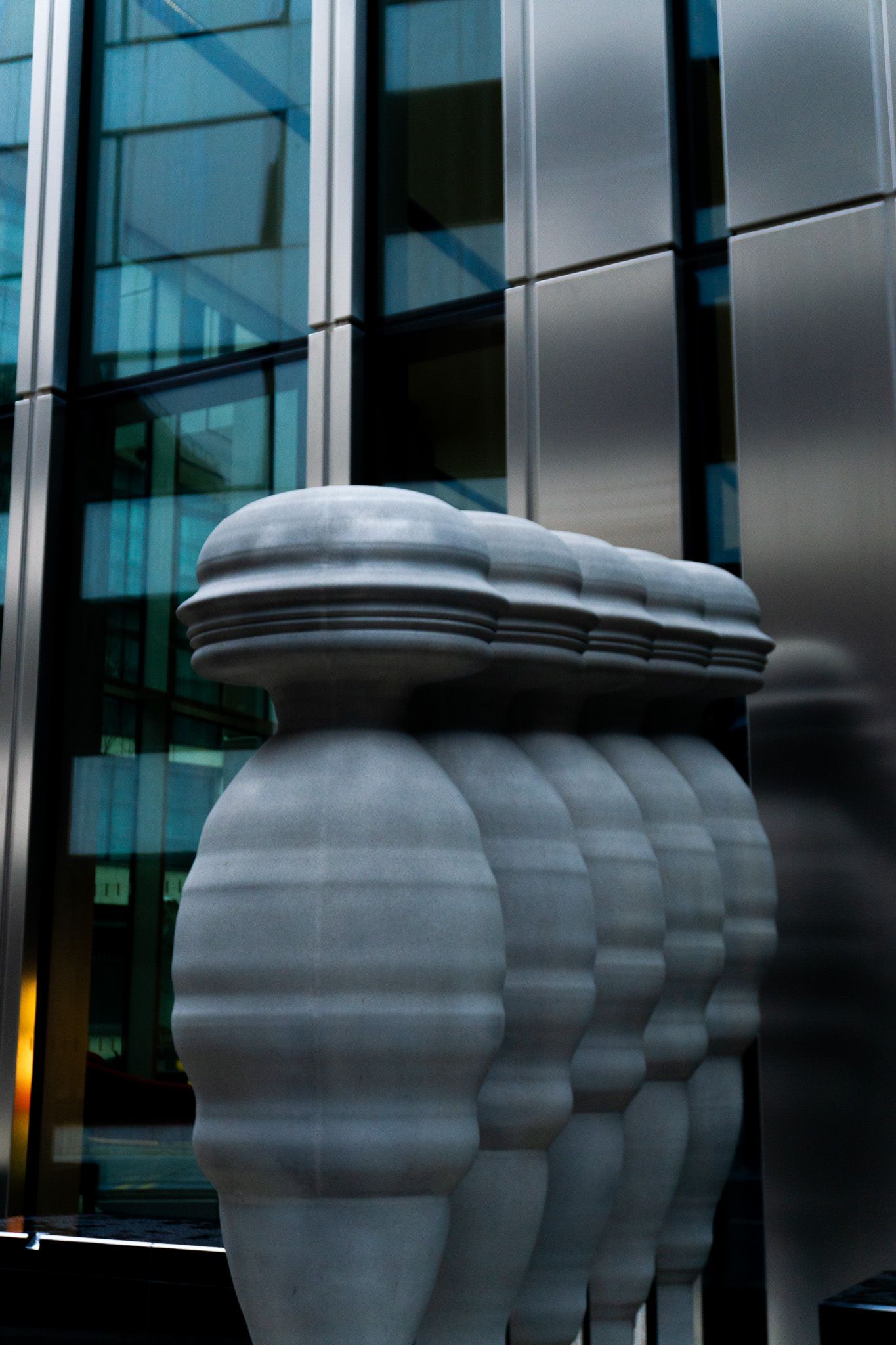 A close-up of a white stone column with bulbous details, set against a modern glass and steel building facade.
Reizen - Lynn - Londen