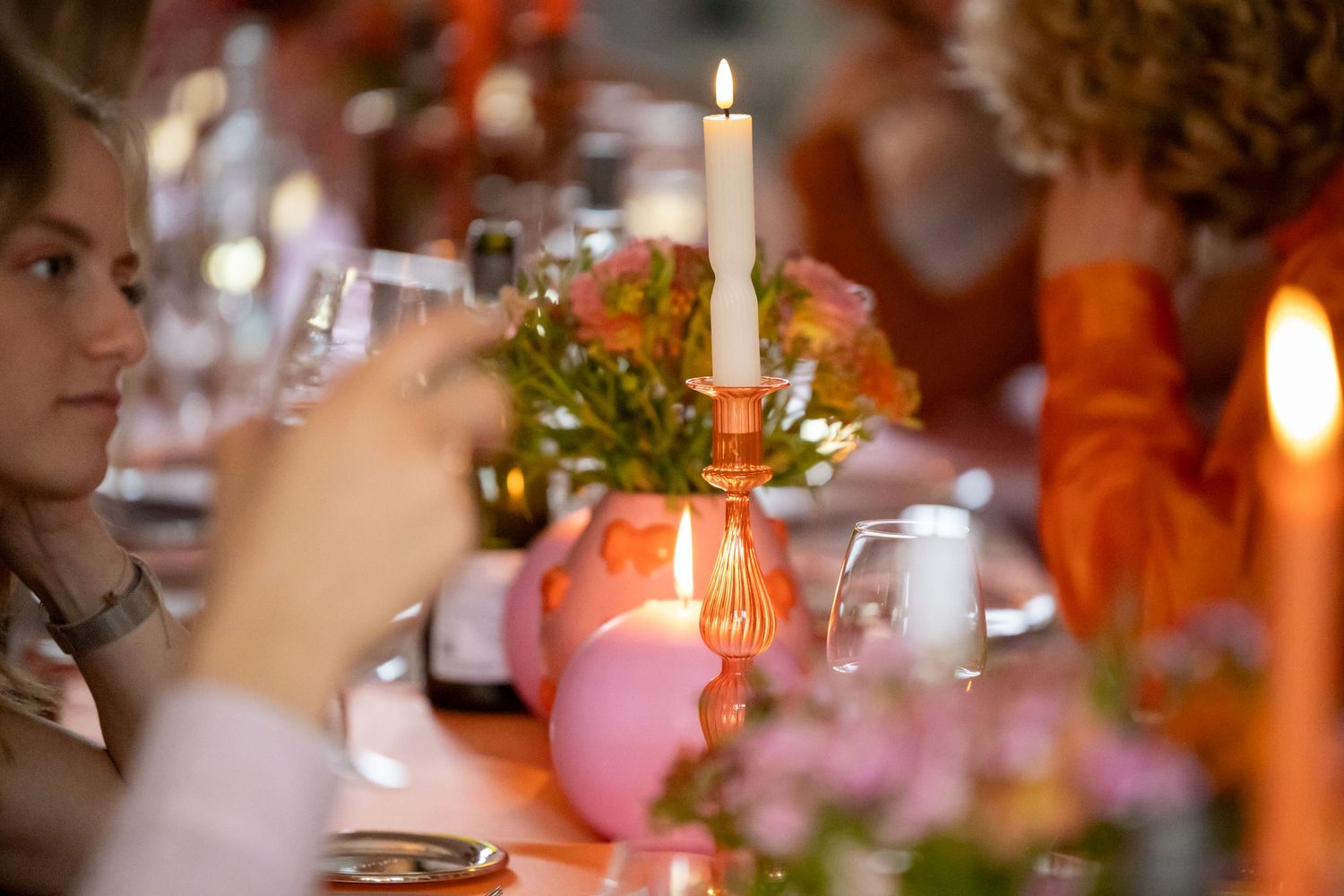 Lit taper candle in orange holder surrounded by pink floral arrangements at an elegant dinner party table.
Evelijn - 21 Diner - Event shoot