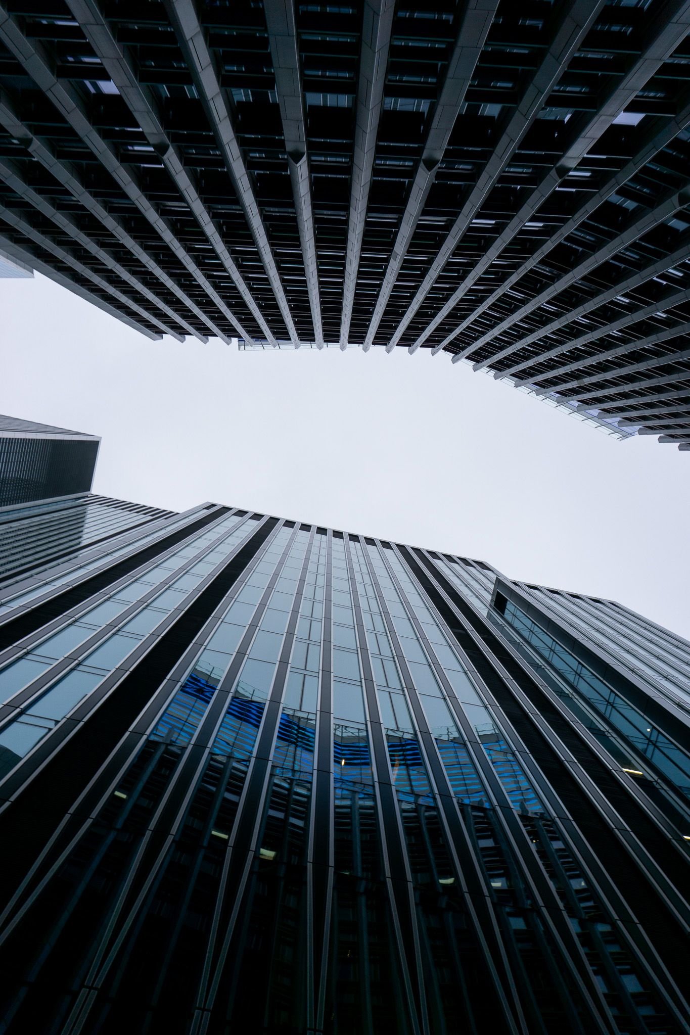 Low-angle view of modern glass skyscrapers converging against overcast sky, showcasing dramatic urban architecture.
Reizen - Lynn - Londen