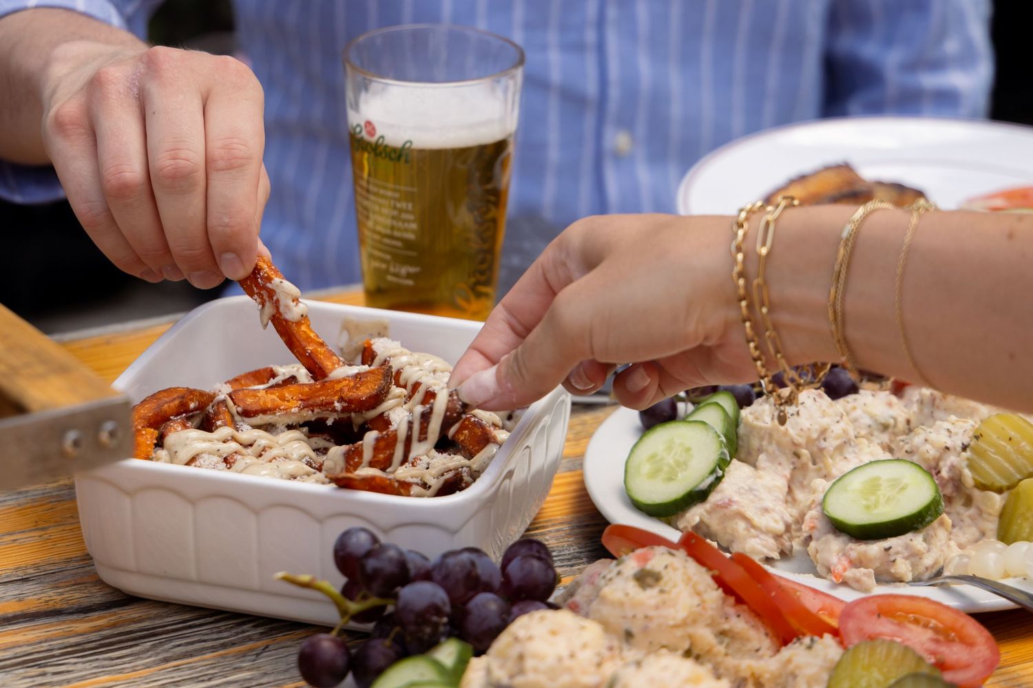 Two people sharing a platter with vegetables, fries and salads, accompanied by a glass of cold beer.
Yips - BBQ - Brandingshoot