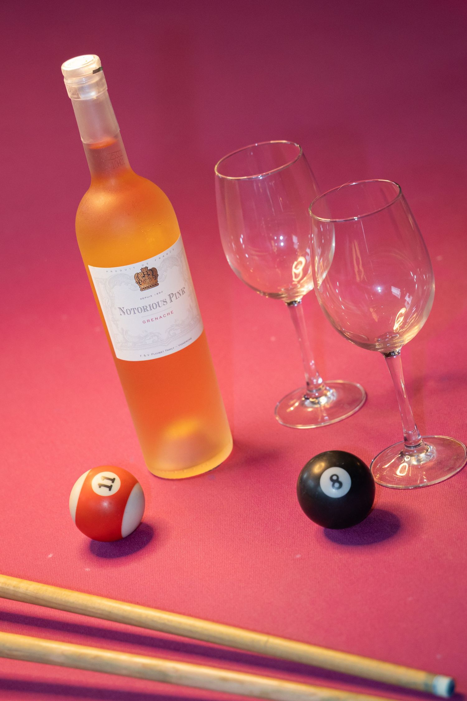 Rose wine bottle with two empty glasses and billiard balls on a pink pool table.
Yips - Brandingshoot