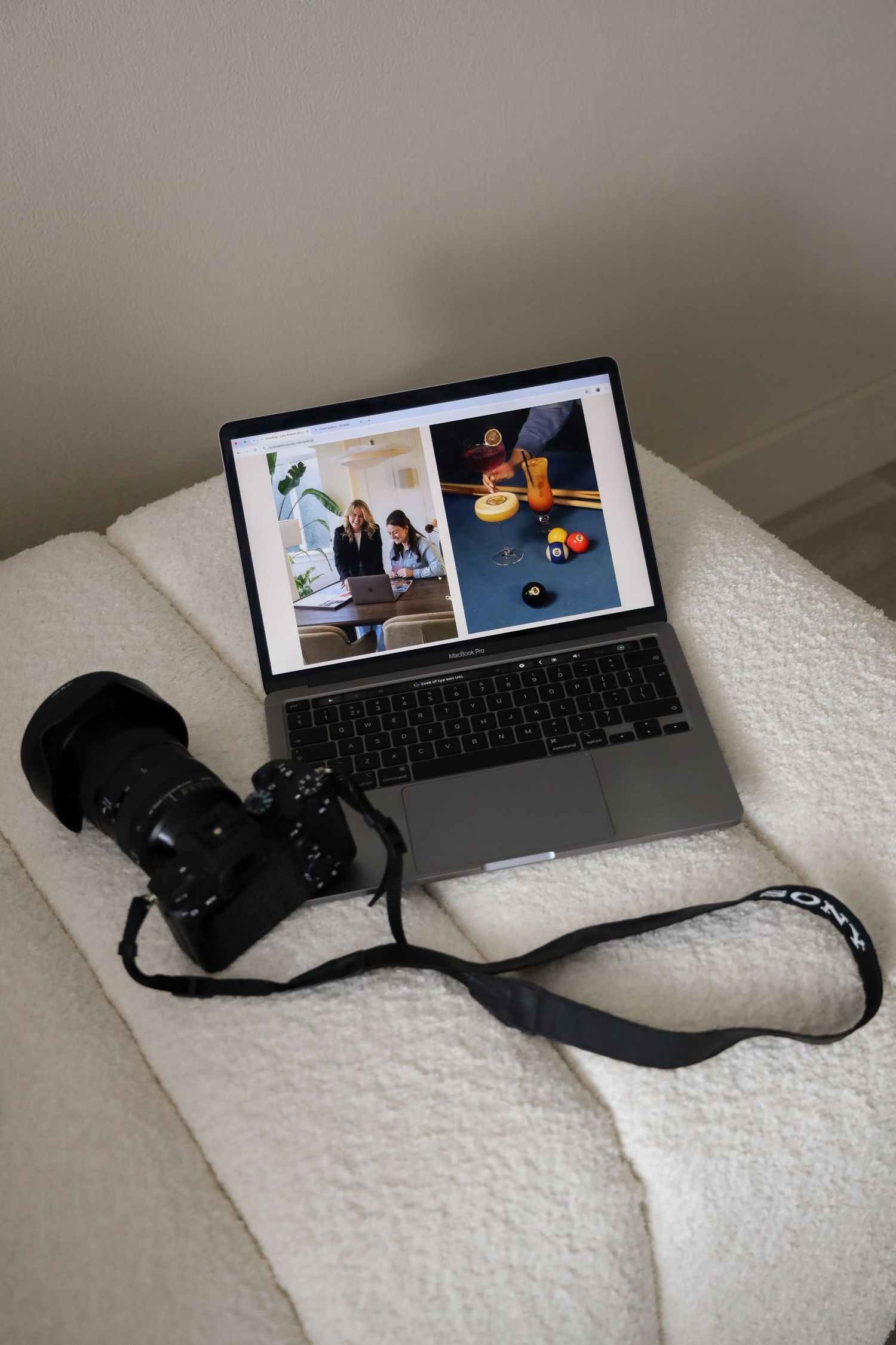 A DSLR camera with strap beside an open MacBook displaying photography portfolio images on a white chair.