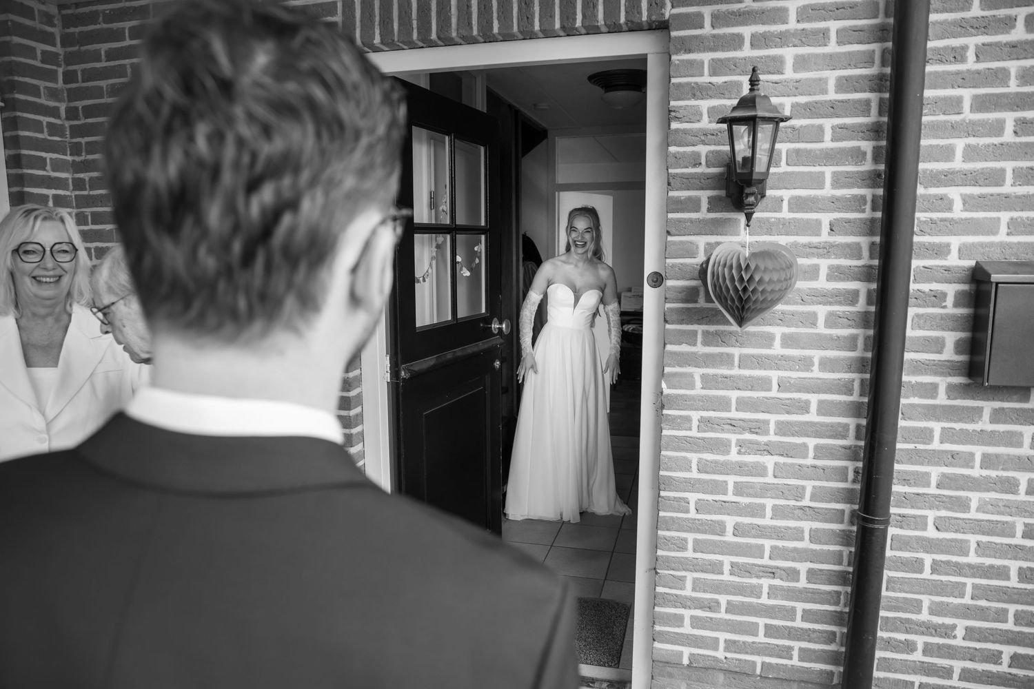 Black and white wedding photo of bride in doorway as groom sees her for the first time.