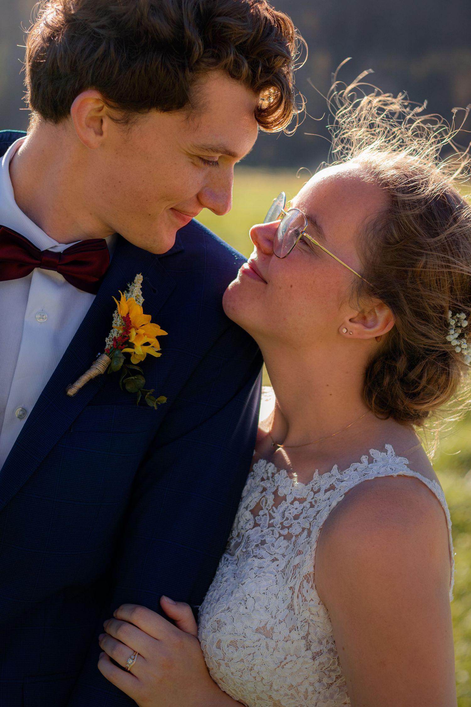 Bride and groom gazing at each other in golden sunlight with sunflower boutonniere.