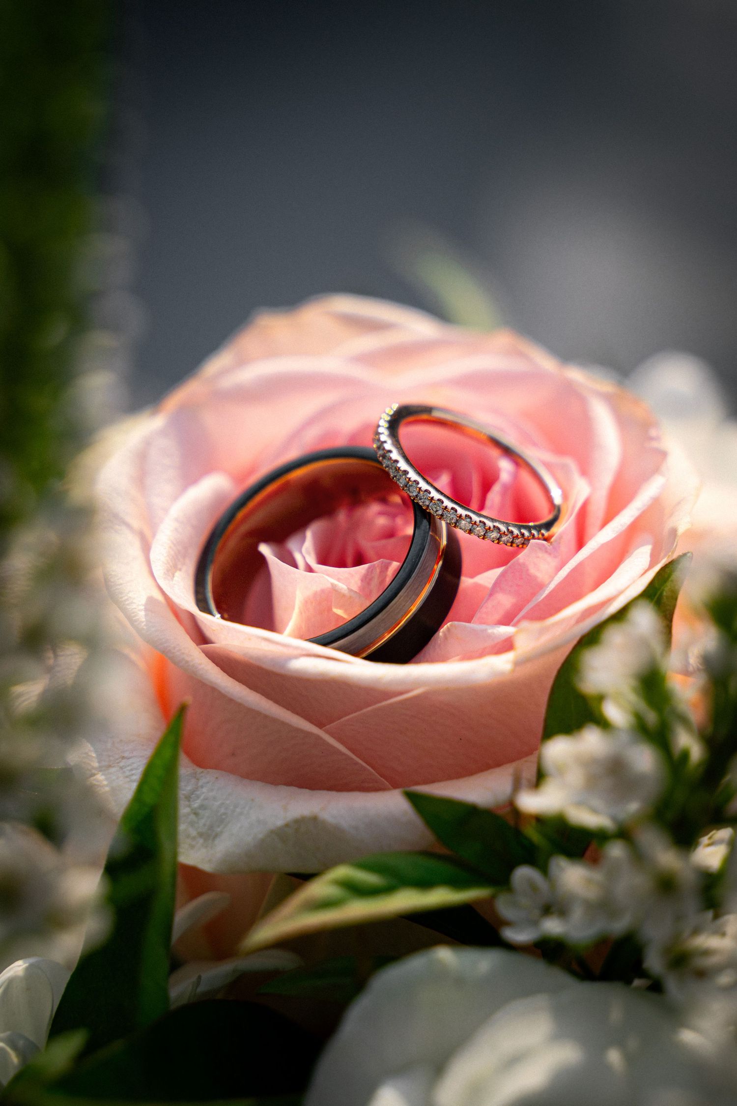 Two wedding rings resting inside a pink rose in a bridal bouquet.