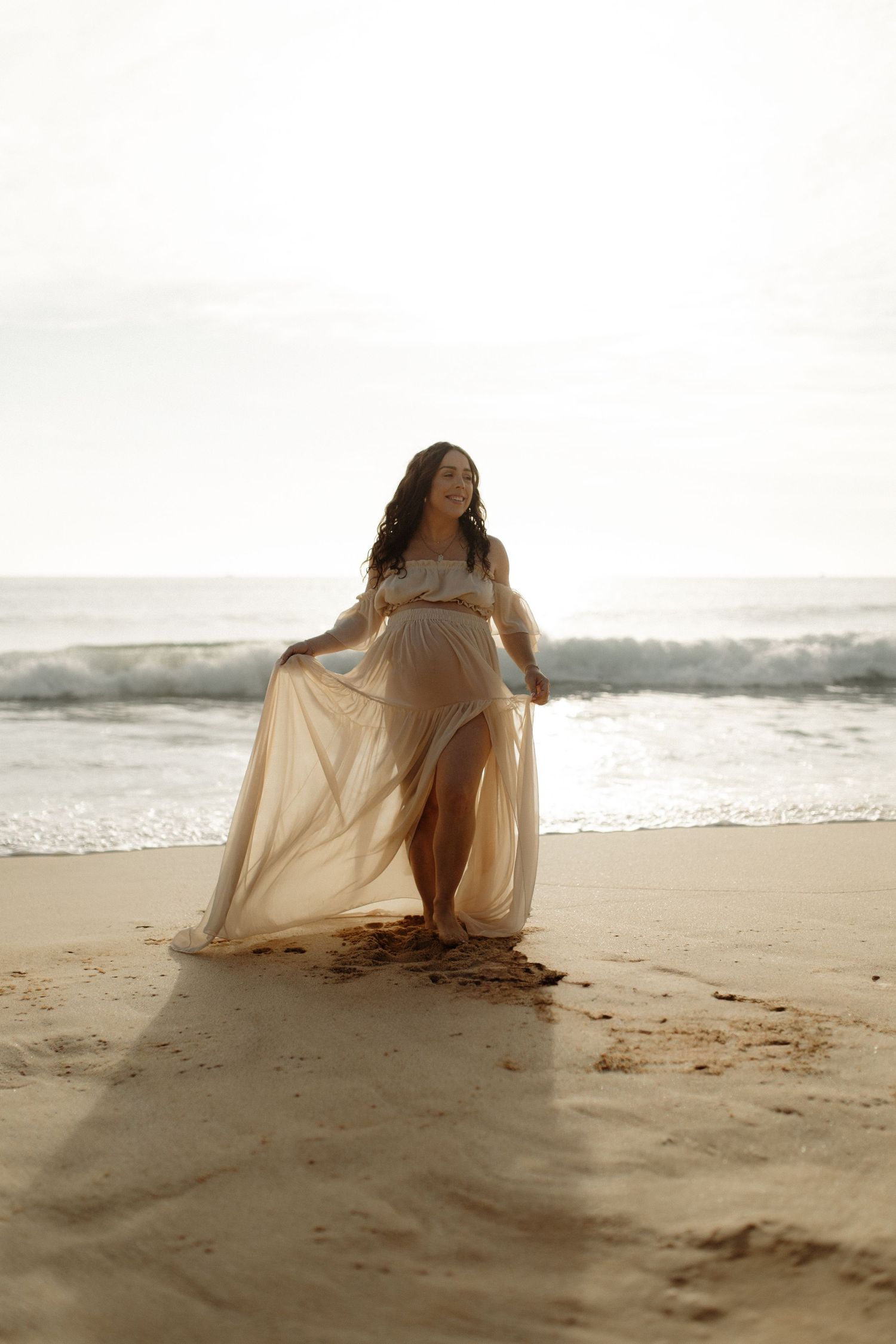 Maternity photo at the beach at sunrise in a beautiful dress