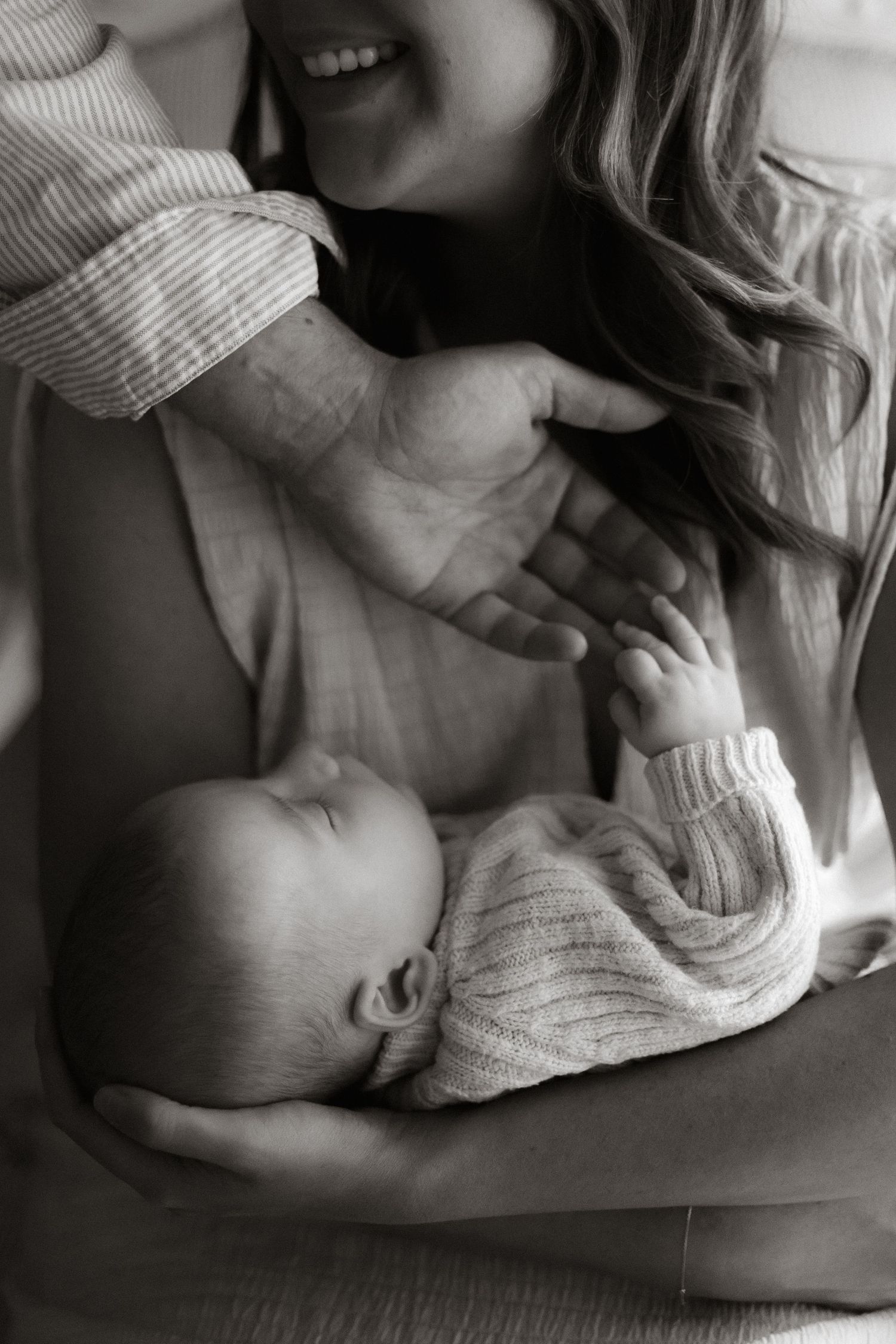 Dad holding baby son's hand while in Mother's arms