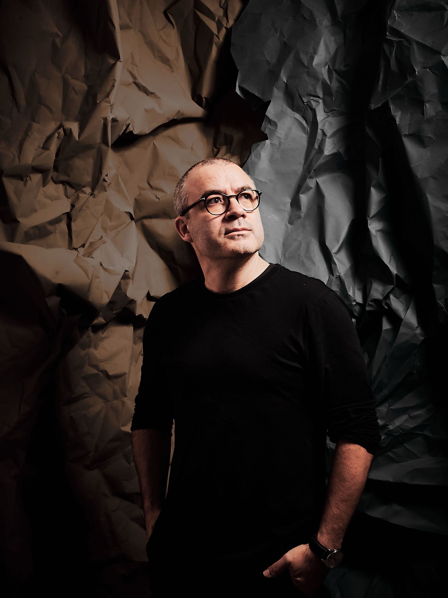 A dramatic portrait series against a dark textured background shows a figure in glasses with dramatic side lighting.