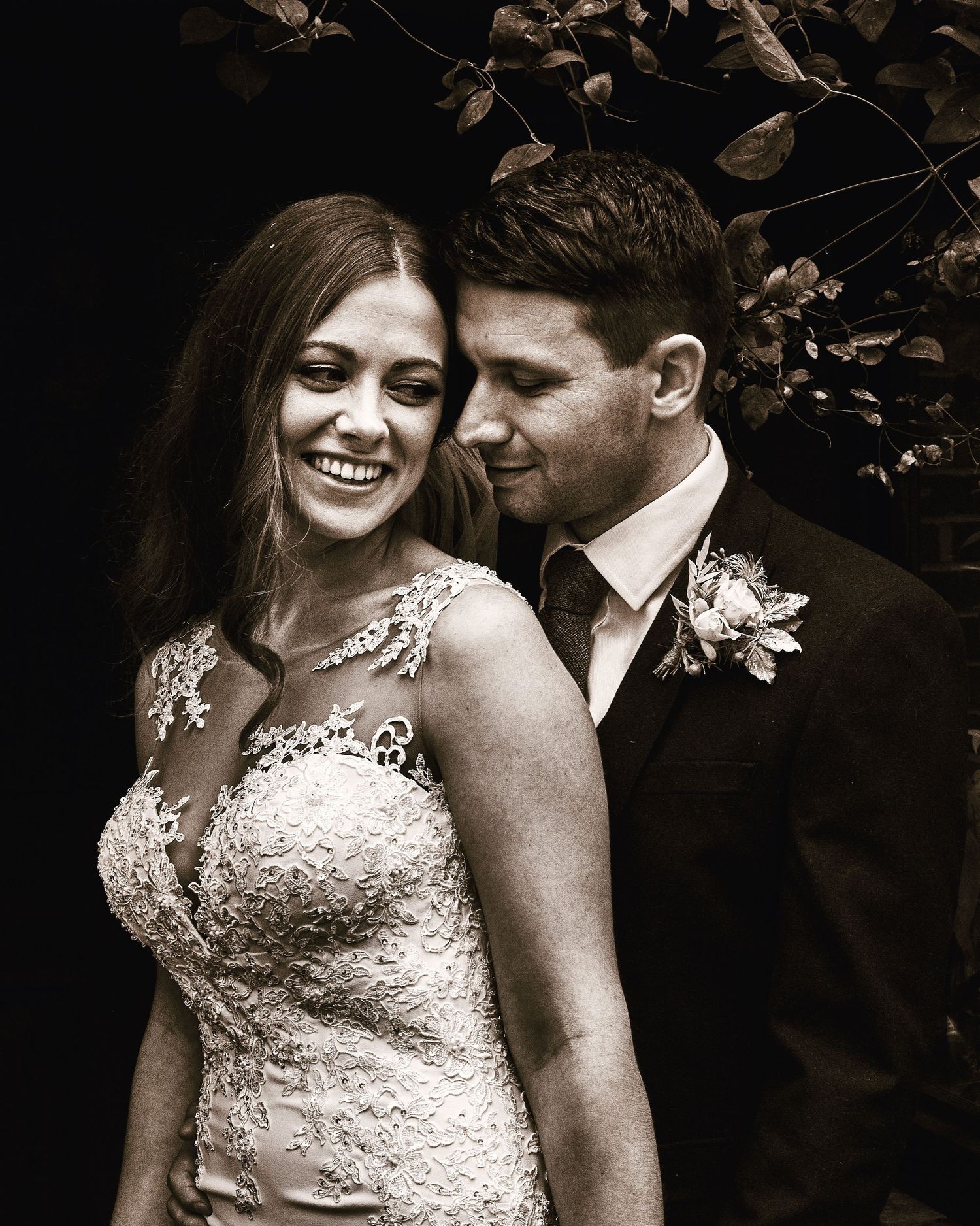 Black and white wedding photograph of a couple sharing an intimate moment outdoors in formal attire.