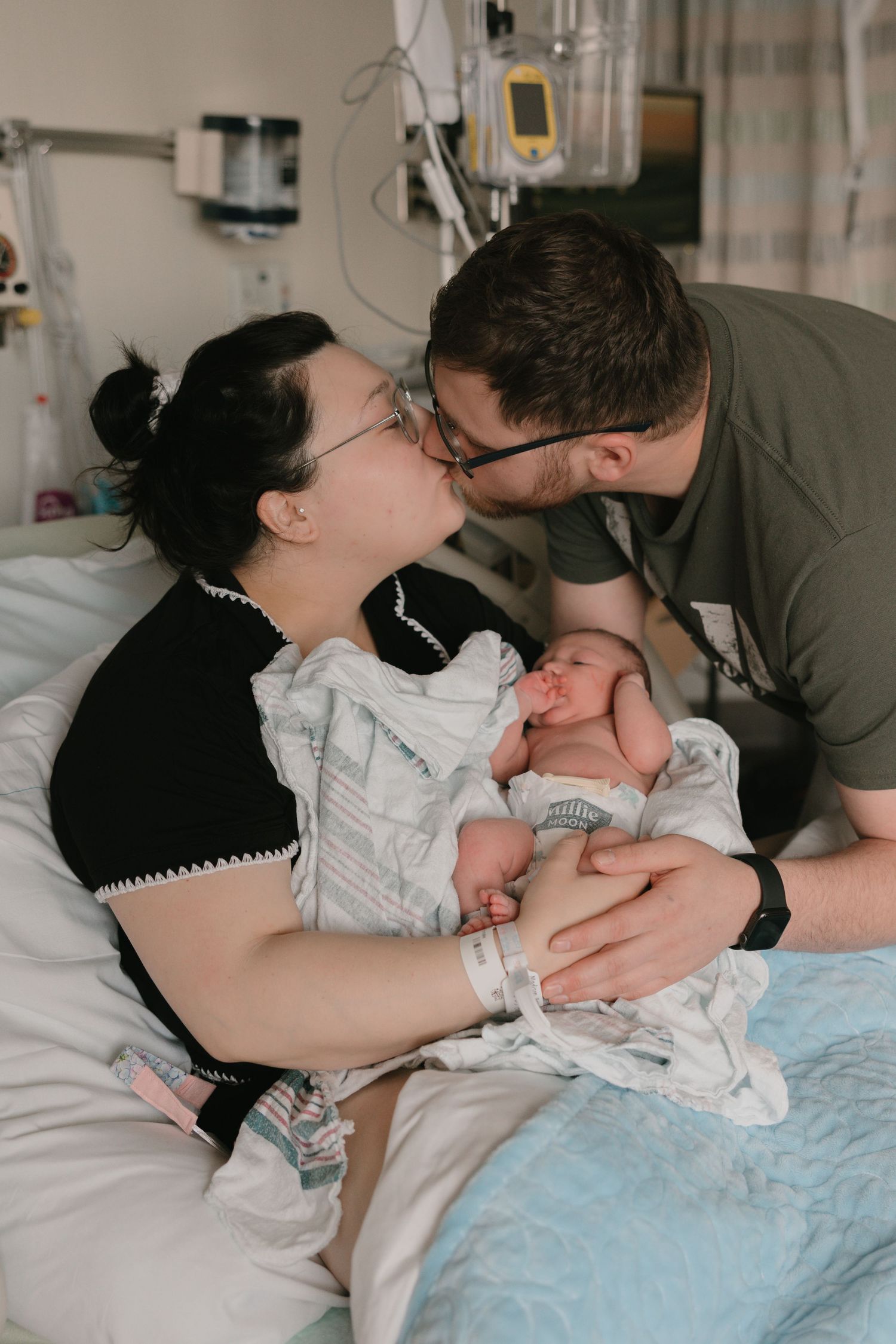 Parents share tender moments with their newborn baby while resting in a hospital bed.