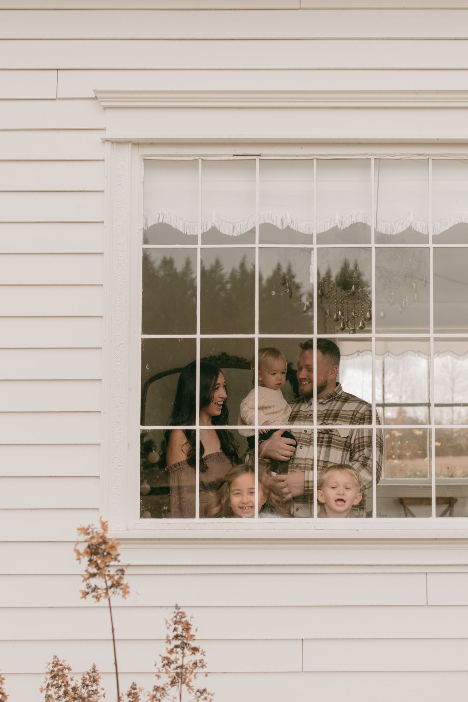 A family shares joyful moments together while looking through a white-framed window of their home.