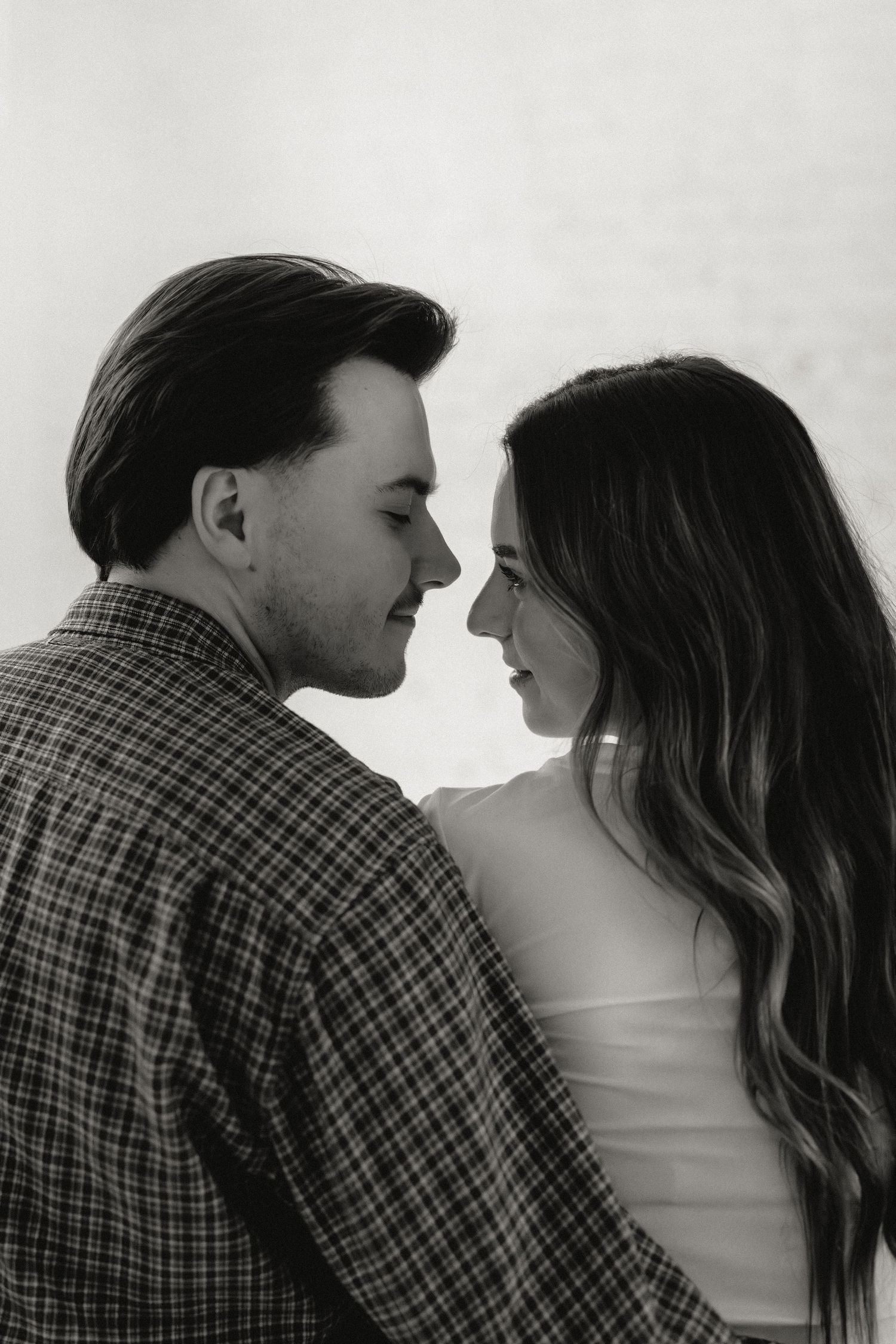 A romantic black and white photo sequence showing a couple in a plaid shirt and white top getting closer to kiss.