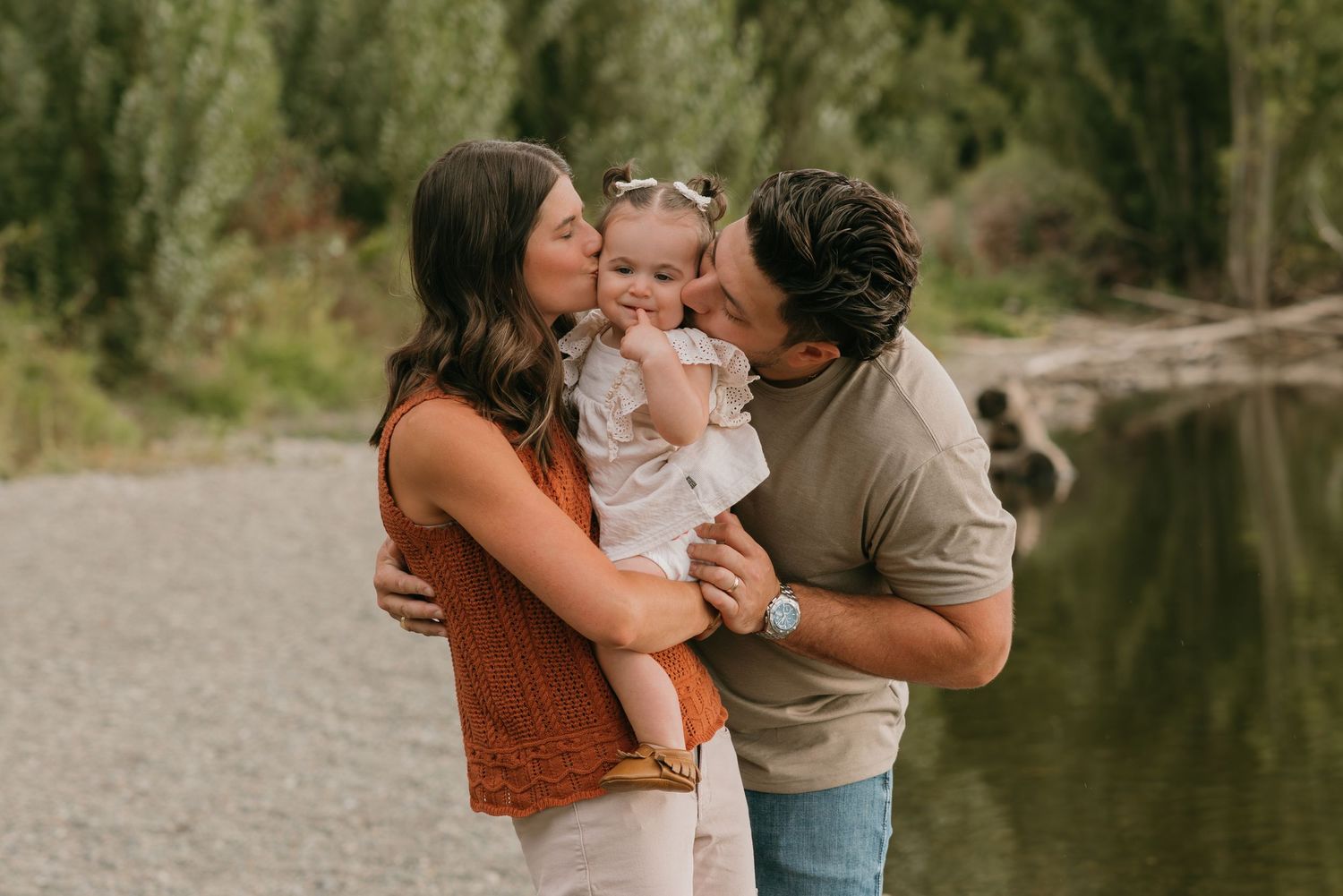 A family shares tender moments together by a scenic lake during an outdoor photo session.