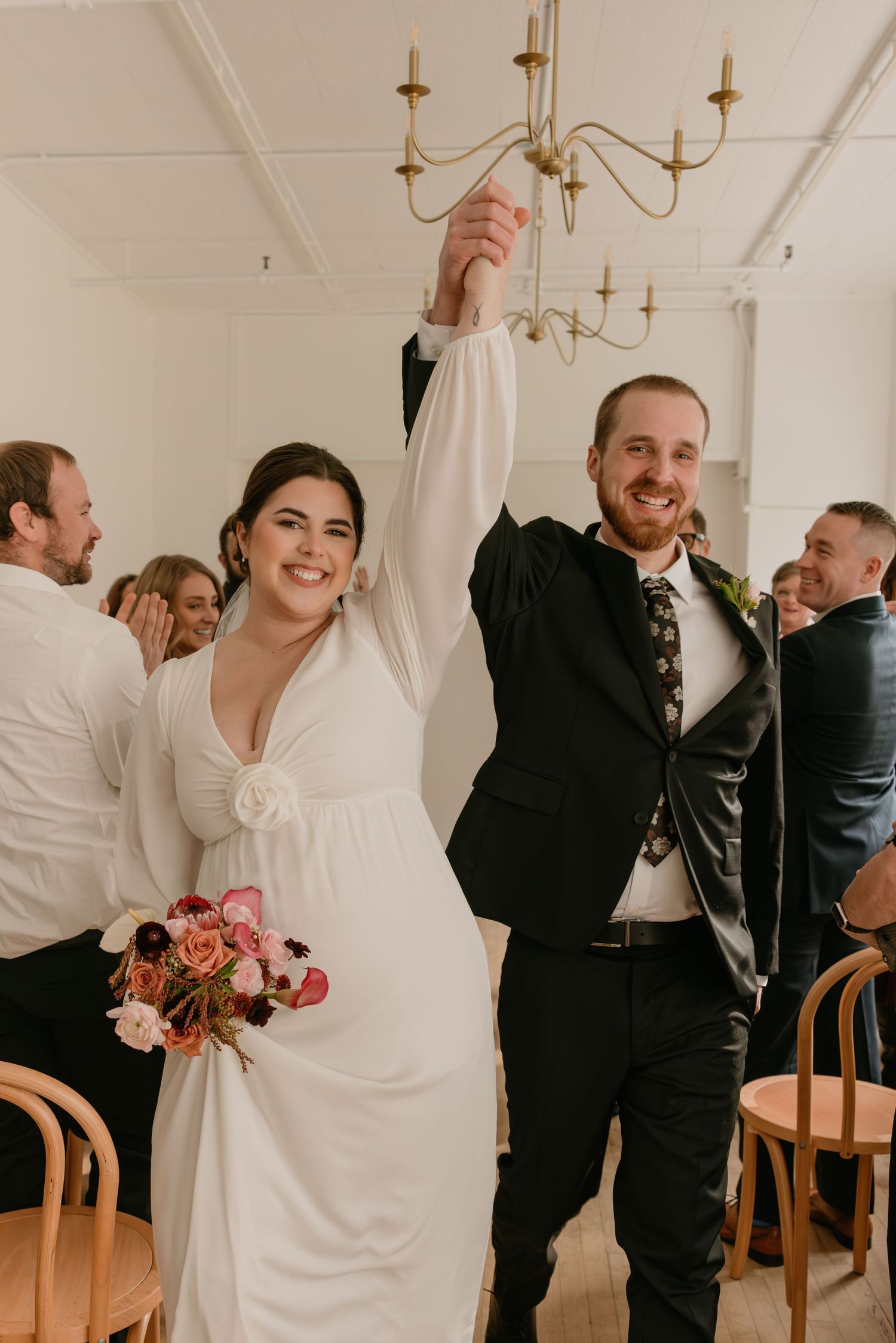 Candid wedding reception moments showing couples dancing and embracing in an elegant white room with chandeliers.