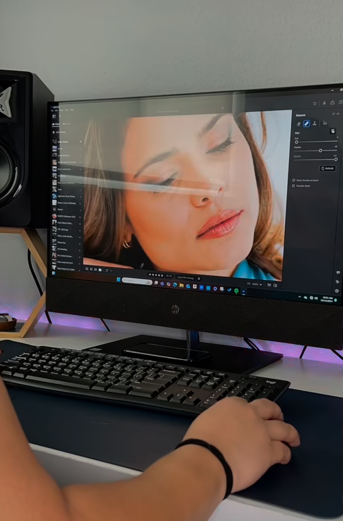 A computer monitor displaying photo editing software with a portrait visible on screen.