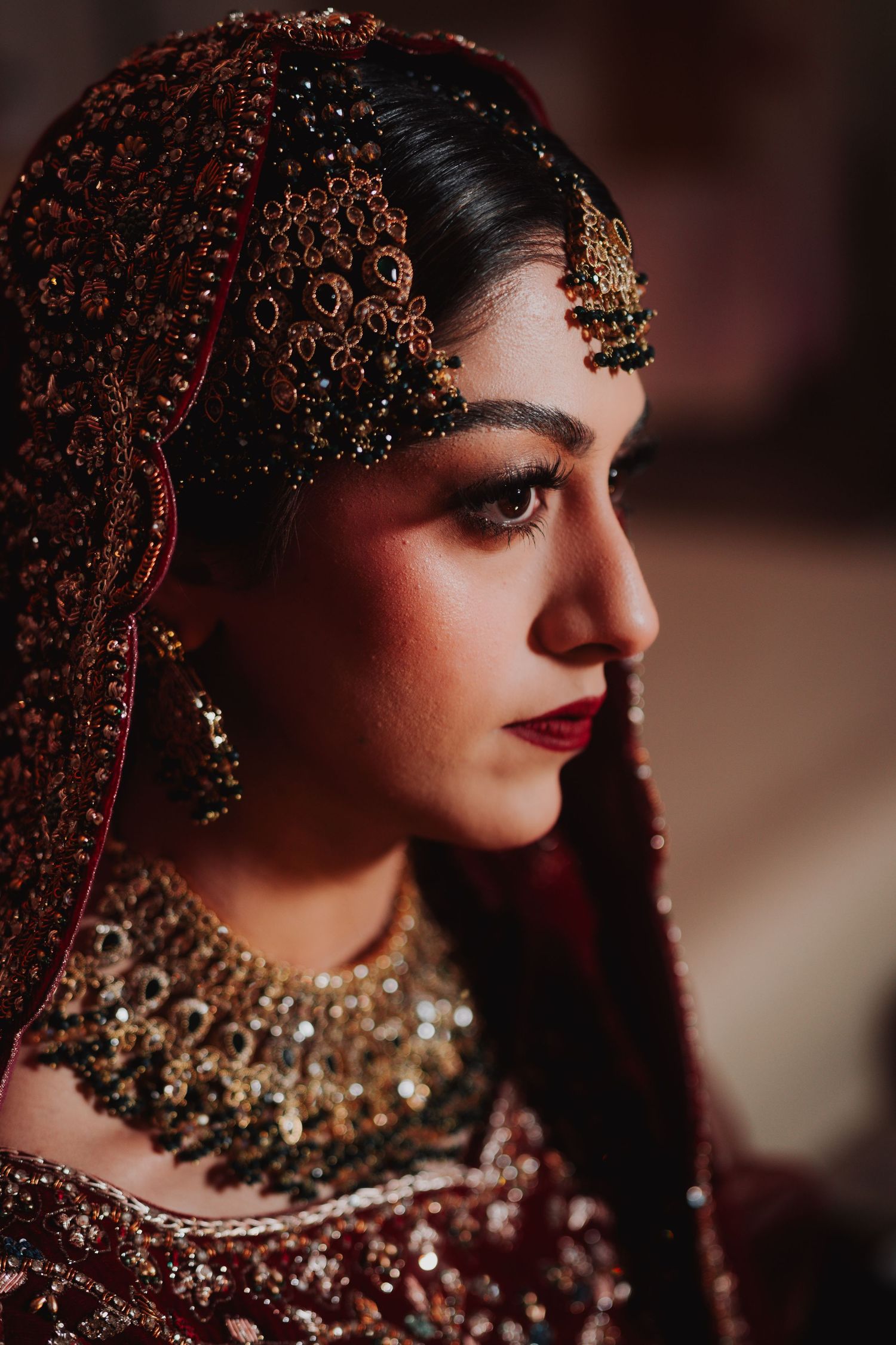 Close up portrait showcasing intricate South Asian bridal jewelry and makeup details.