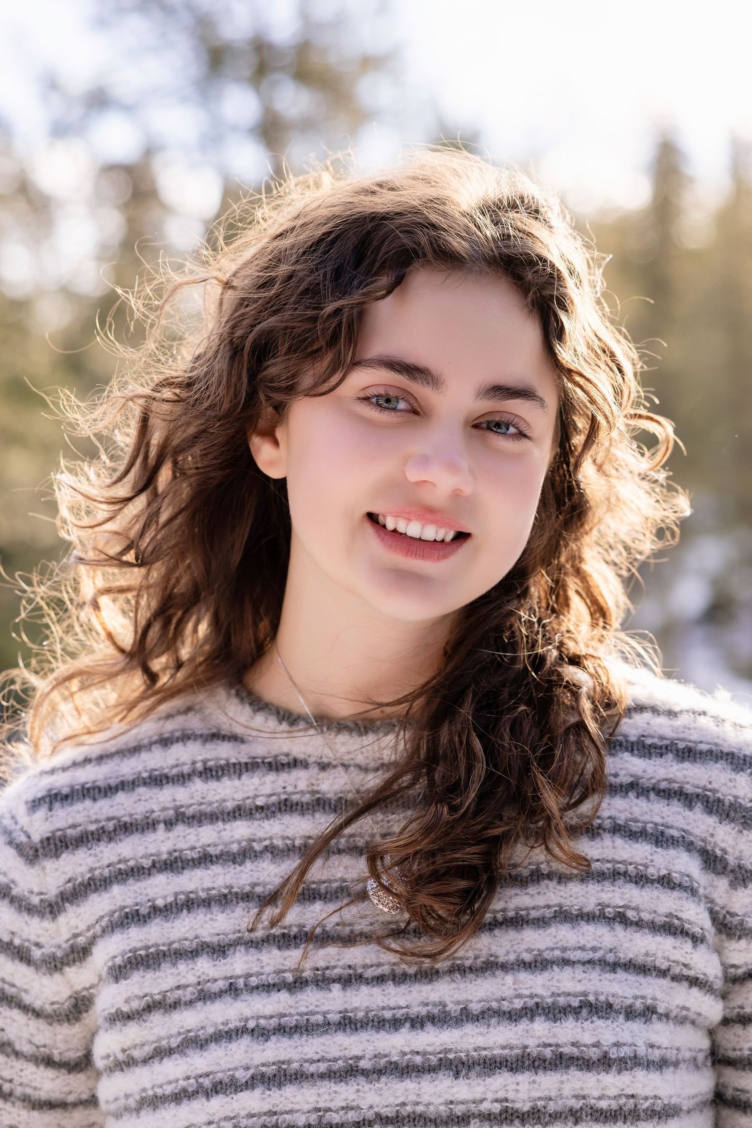 Headshot of a young women with her backlighted by the sun