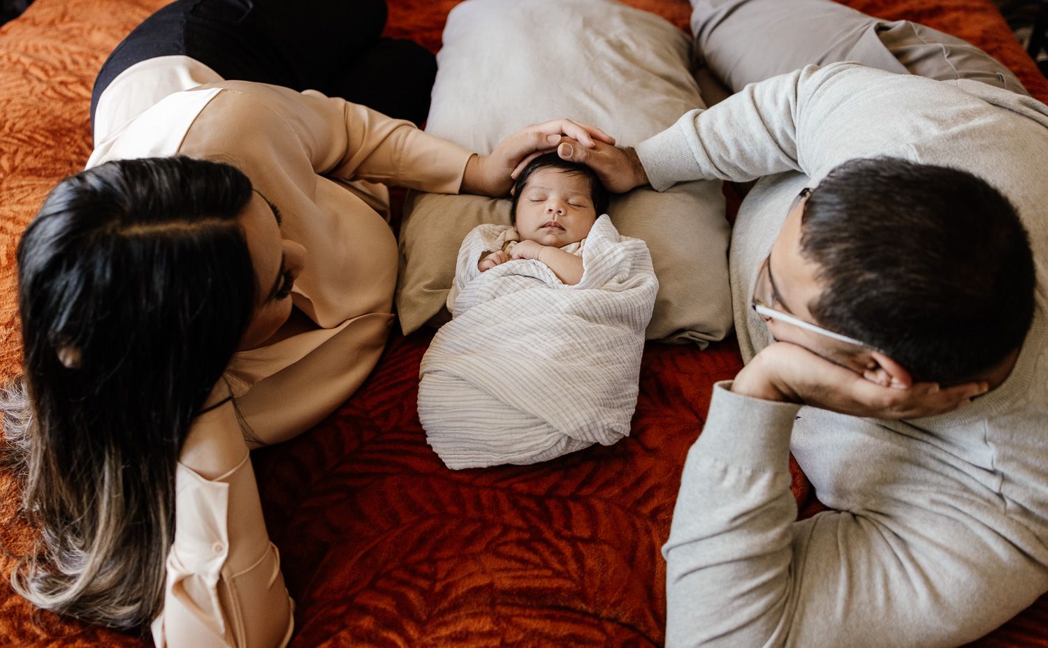 Baby lays in between mom and dad at newborn photo session in Bay Area