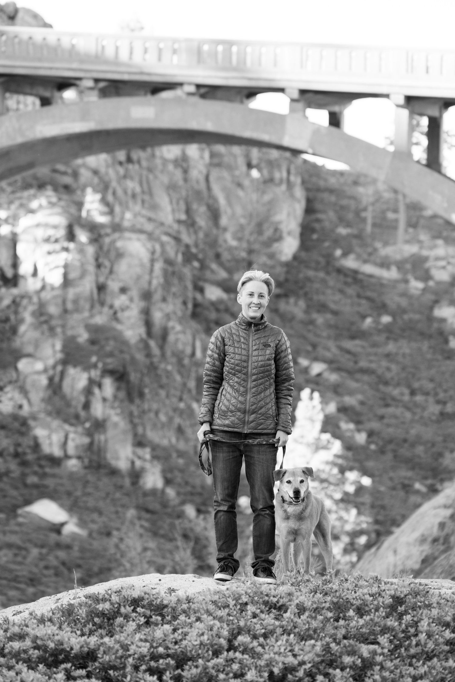 Woman stands under a bridge with her dog in Truckee